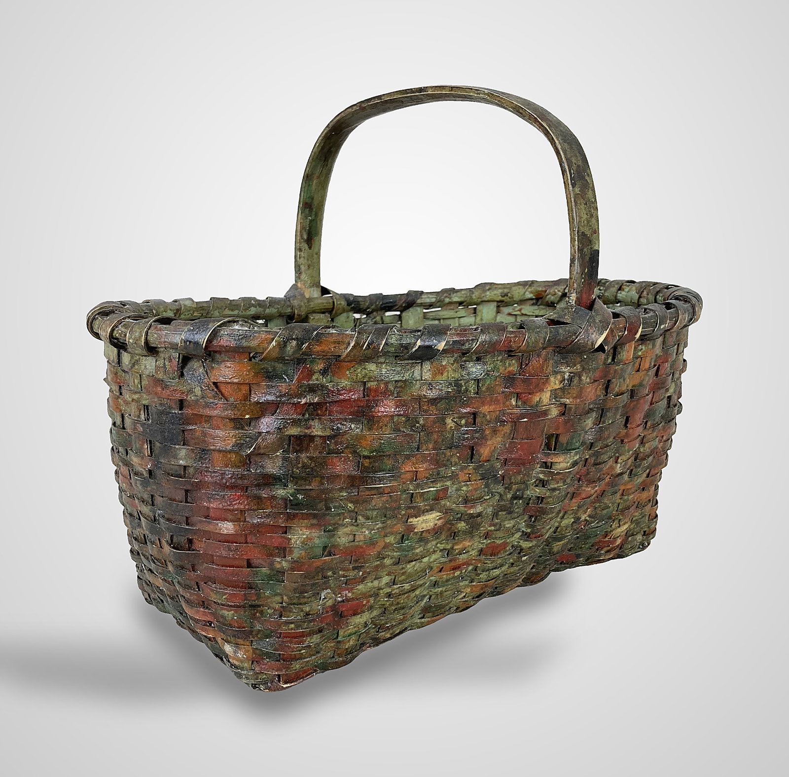 Early Painted Gathering Basket: This nicely woven split oak gathering basket features a multi-colored painted finish, an integrated handle, an oval rim, and a rectangular base. It displays a worn, aged patina. It measures approximat