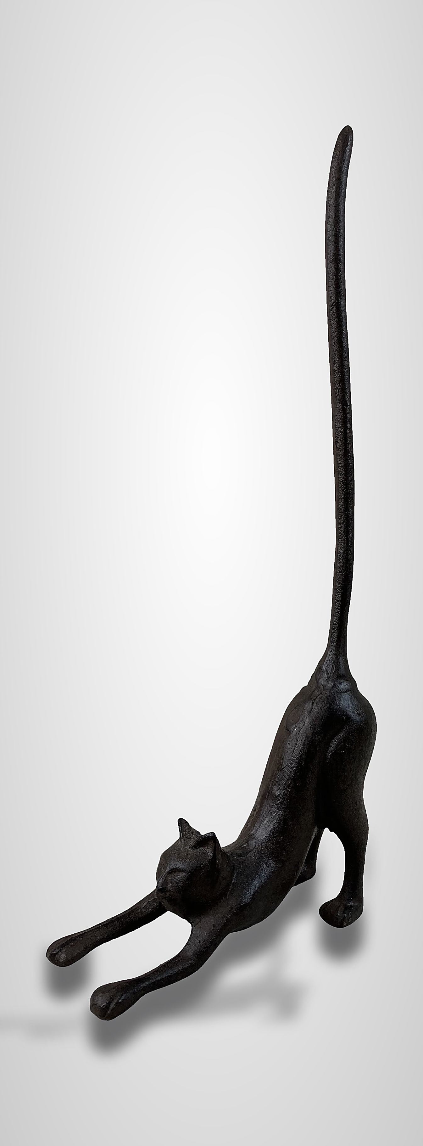 Cast Bronze Cat Figurine: Charming and elegant piece features a cat in a stretching pose with its long tail extended, showcasing careful sculpting and casting. Dimensions are approximately 18 in. H x 7 1/4 in. W x 2 1/2 in. D.