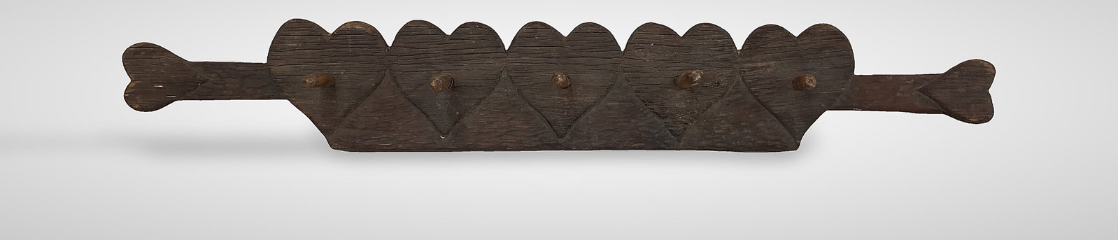 Folk Art Carved Heart Coat Rack: This carved wood coat rack features a repeating heart motif and shaved texture, accented by shaved wooden pegs. It displays a warm, aged patina and measures approximately 39 in. H x 5 3/4 in. W. The