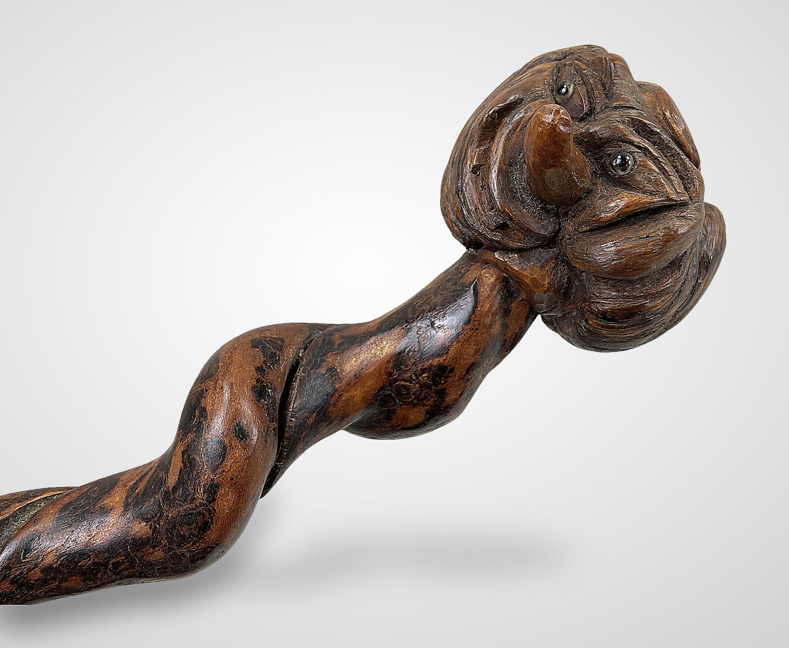 Folk Art Carved Grotesque Cane: Cane crafted from burl wood, highlighting the natural branch formation with twisting shaft.Standout piece features a carved face that masterfully utilizes the woods natural burl shape. Demonstrates