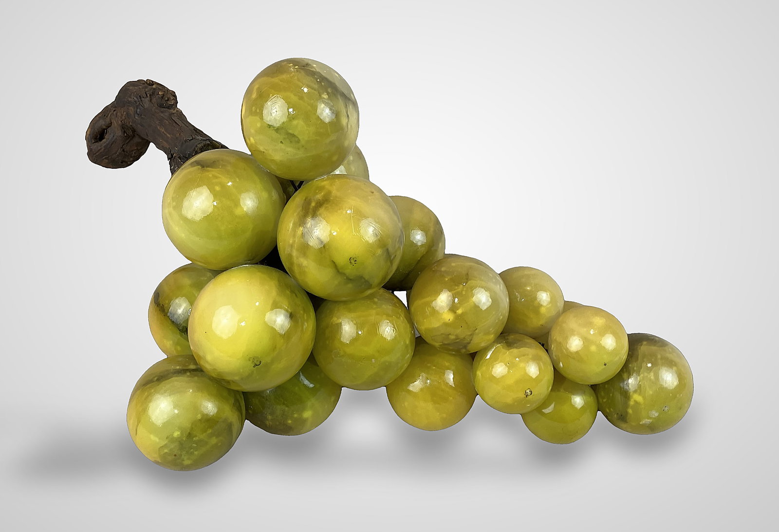 Massive Alabaster Grapes: Substantial decorative piece featuring large yellow stone grapes accented by a twig element that offers a contrasting texture, measuring approximately 9 in. H x 15 in. W x 8 in. D and in good