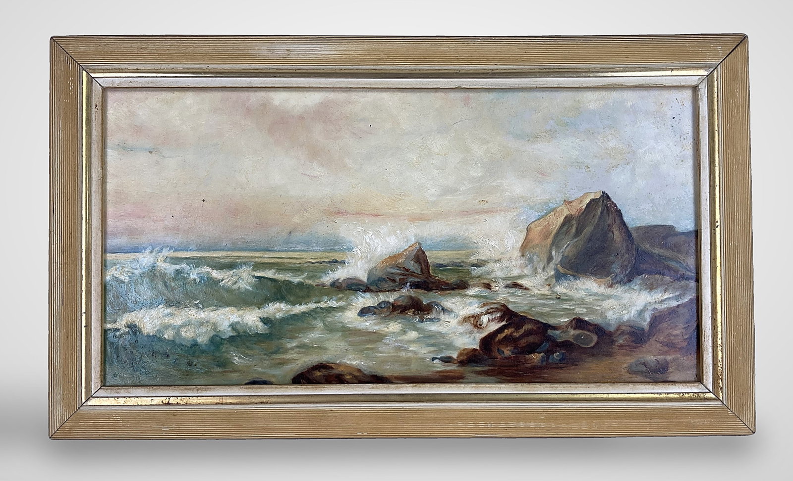 Early 20th Century, Coastal Seascape, Oil Painting: This early oil on board painting depicts a dramatic coastal scene featuring rocky outcrops and crashing waves, rendered with a textured impasto technique. It is housed in a light-colored wood frame.