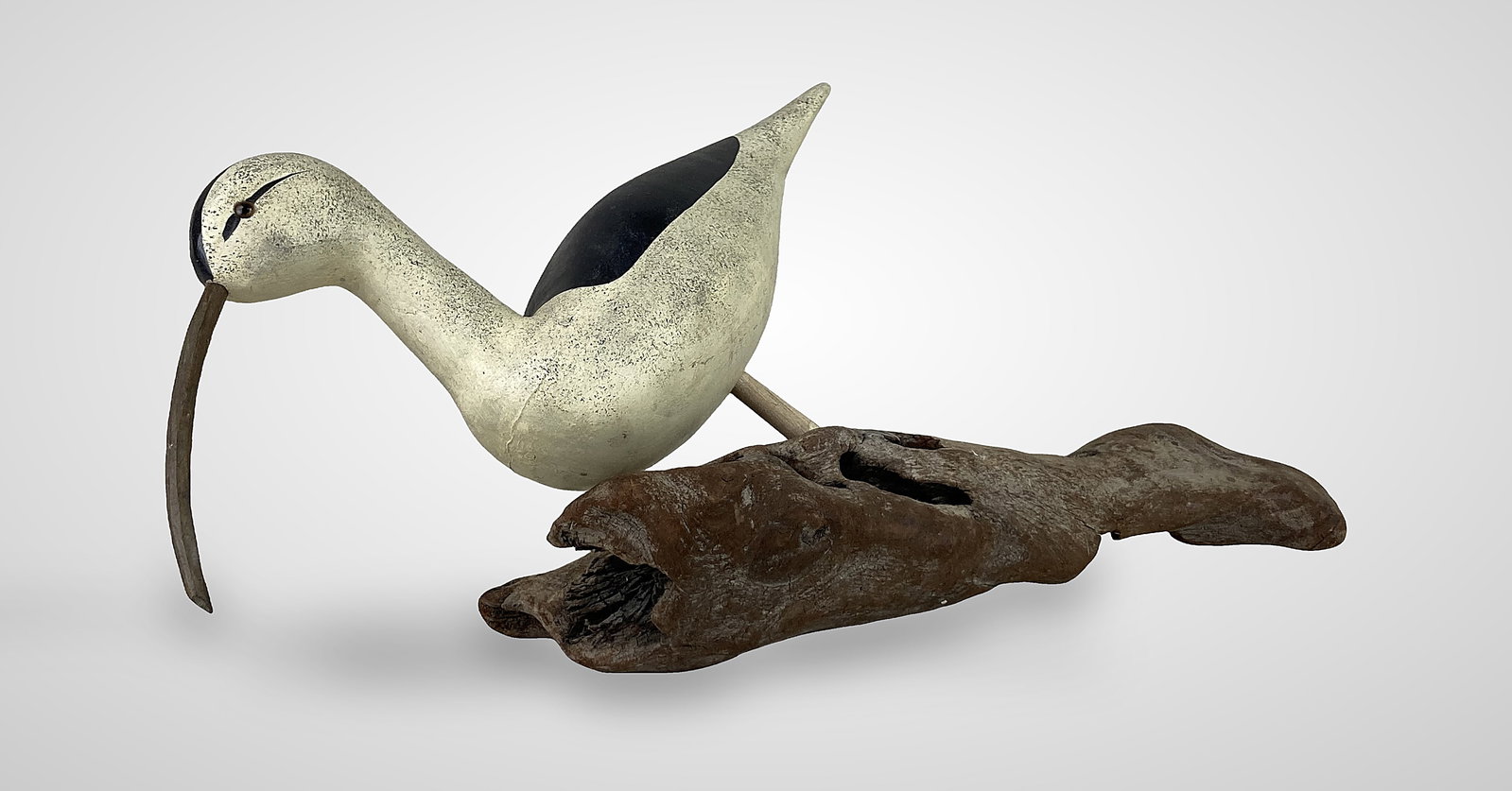 Polychromed Folk Art Shorebird Sculpture: This hand-carved and hand-painted sculpture features a white and black body accented by delicate black speckling and a prominent black stripe running through the eyes and head. It is finished with