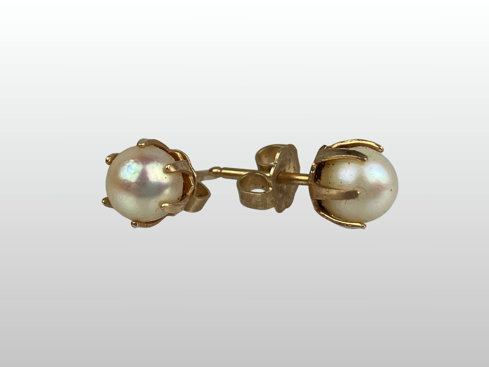14KT Pearl Stud Earrings: These delicate earrings feature beautiful, pale, round pearls set within elegant prong settings. Each piece is marked for 14 KT gold content. Dimensions: approximately 1/4 in. H x 1/8 in. W. Total