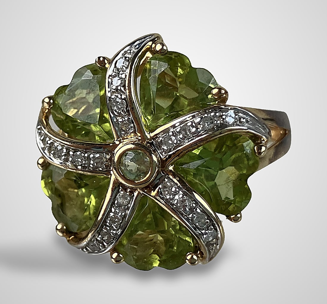 14 KT Gold Diamond and Peridot Ring: This ring features a warm 14 KT yellow gold band and setting, showcasing a central flower formation with five heart-shaped peridot gems surrounded by 20 round-cut diamonds. The ring is a size 6 and