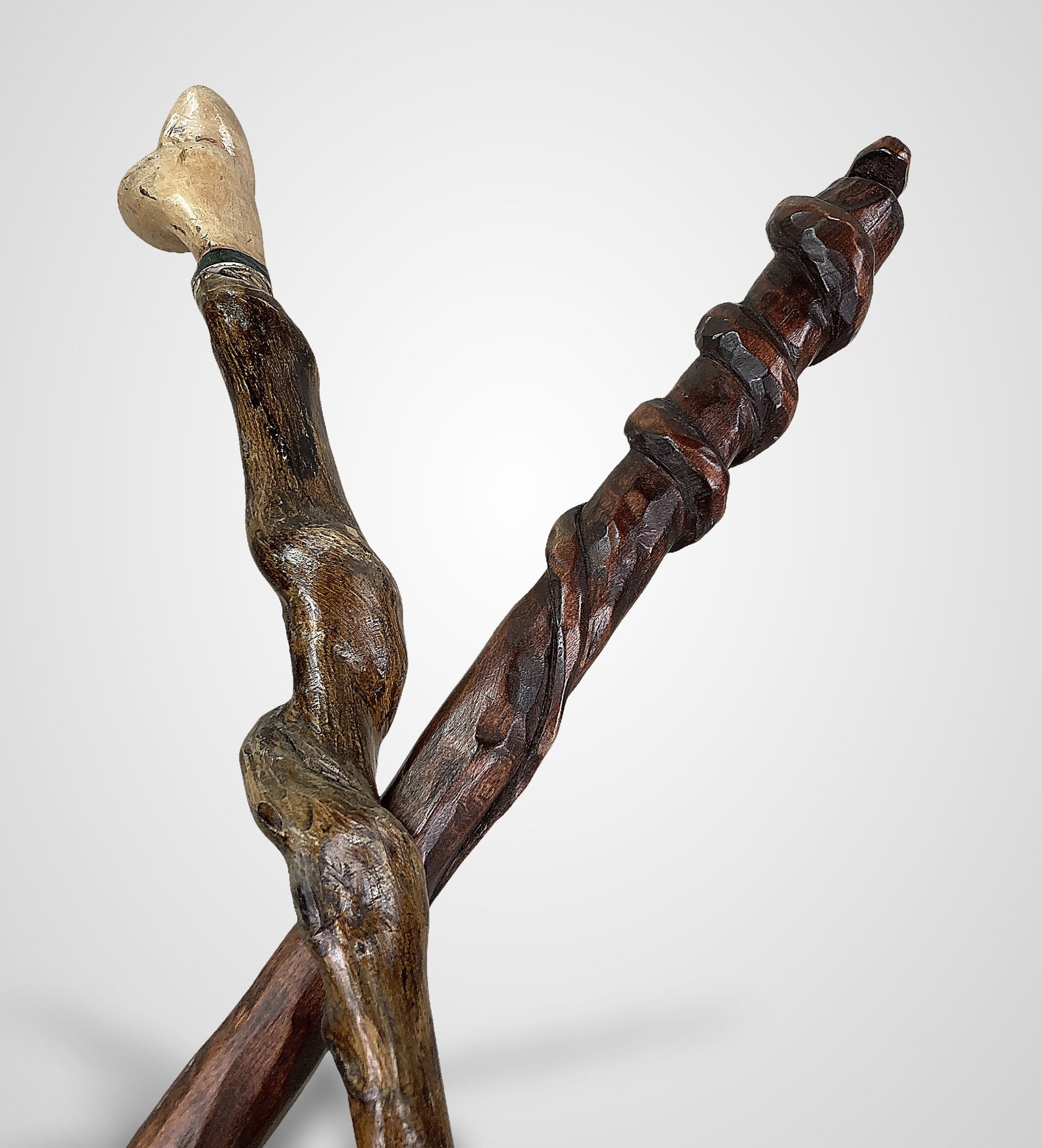 Two Folk Art Carved Canes: Features distinct craftsmanship; one cane is highlighted by a carved snake form that encircles the shaft, while the other showcases a naturally curved wood shaft paired with a lighter-wood handle
