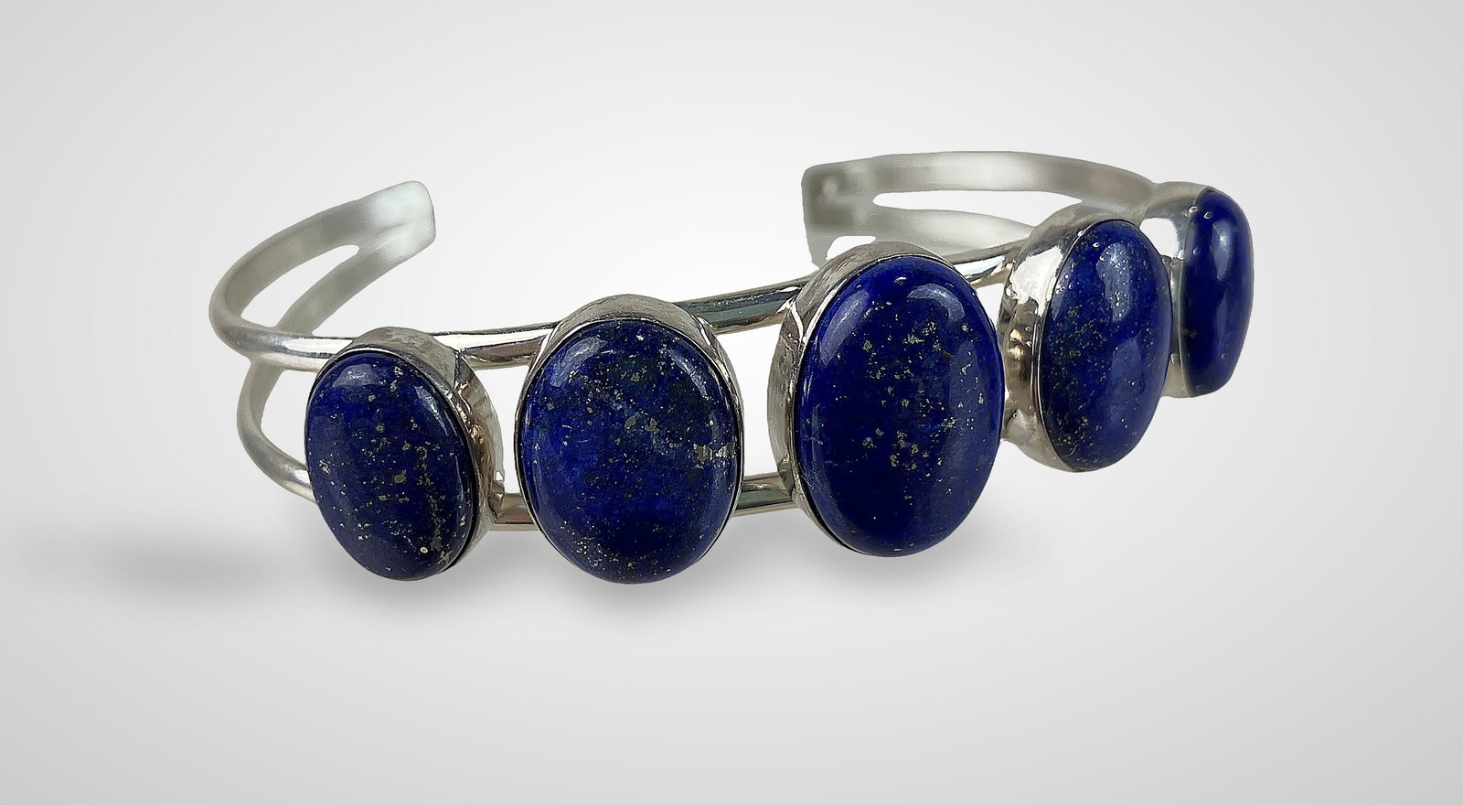 Sterling Silver and Lapis Lazuli Cuff Bracelet: Elegant cuff features oval Lapis Lazuli cabochon amulets throughout, set in sterling silver. The bracelet measures approximately 2 5/8 in. in inner diameter and has a total weight of 23 g, including
