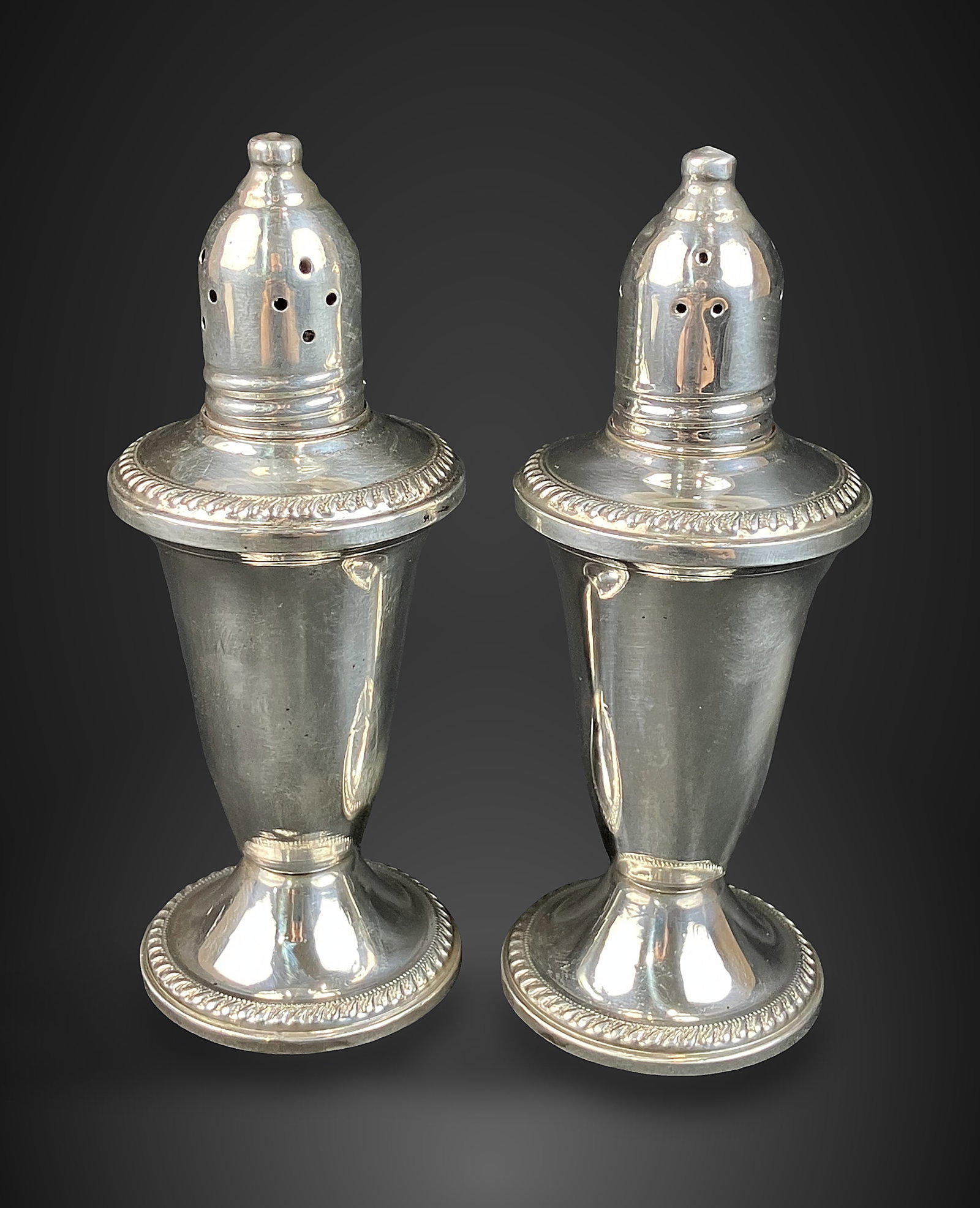 Sterling Silver Salt and Pepper Shakers: Pair of weighted sterling silver shakers is characterized by elegant gadrooned edges. They were produced by Duchin Creations, a prominent mid-century American silver manufacturer based in New York