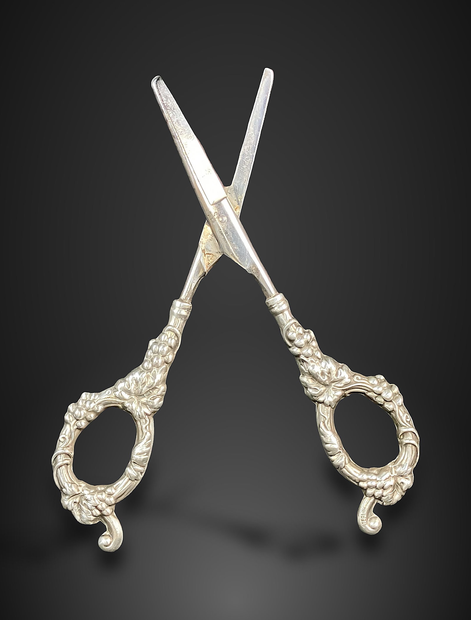 Sterling Silver Handled Grape Shears: Sophisticated shears, crafted by Vom Cleff & Co., feature an elegant grape and vine motif adorning the handle. They measure approximately 6 3/4 in. H x 2 3/8 in. W x 1/4 in. D and are in good