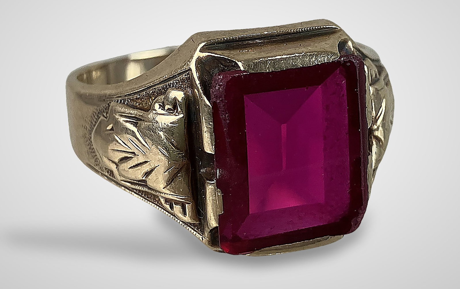 Mens 10KT Gold Art Deco Ring: Ring features a large, rectangular-cut rhodolite garnet set within an ornately decorated Art Deco band. It is marked with the designer's mark and 10KT gold content. The ring is a size 11 and has a