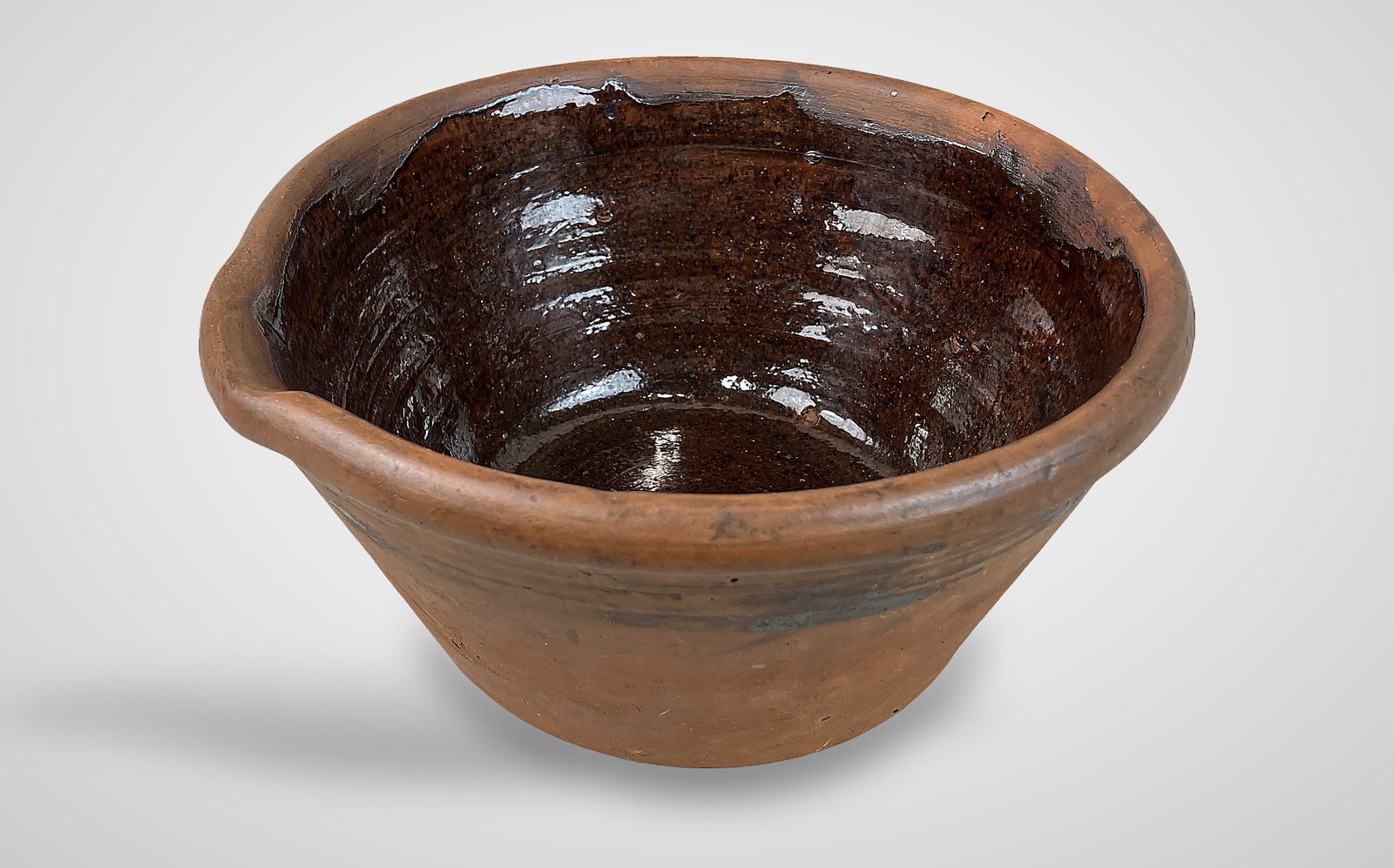 Redware Milk Bowl: Pour bowl features a traditional side spout, a natural redware exterior, and a rich brown glazed interior. It measures approximately 4 1/8 in. H x 8 1/2 in. in diameter and shows some age-appropriate