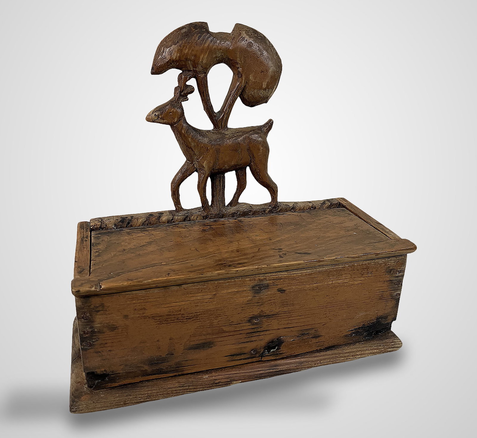 American Folk Art Stag Box: Piece features a hand-carved stag perched beneath a tree form atop the lid. The box measures approximately 9 1/4 in. H x 9 1/4 in. W x 4 1/4 in. D. It shows some wear consistent with its antique age.