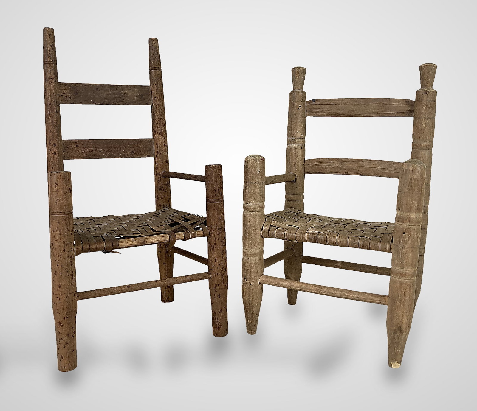 Small Country Ladder Back Doll Chairs: Two charming doll chairs featuring traditional ladder back construction with two slats each, turned legs, and woven splint seats. One chair is crafted in a lighter wood tone, while the other features