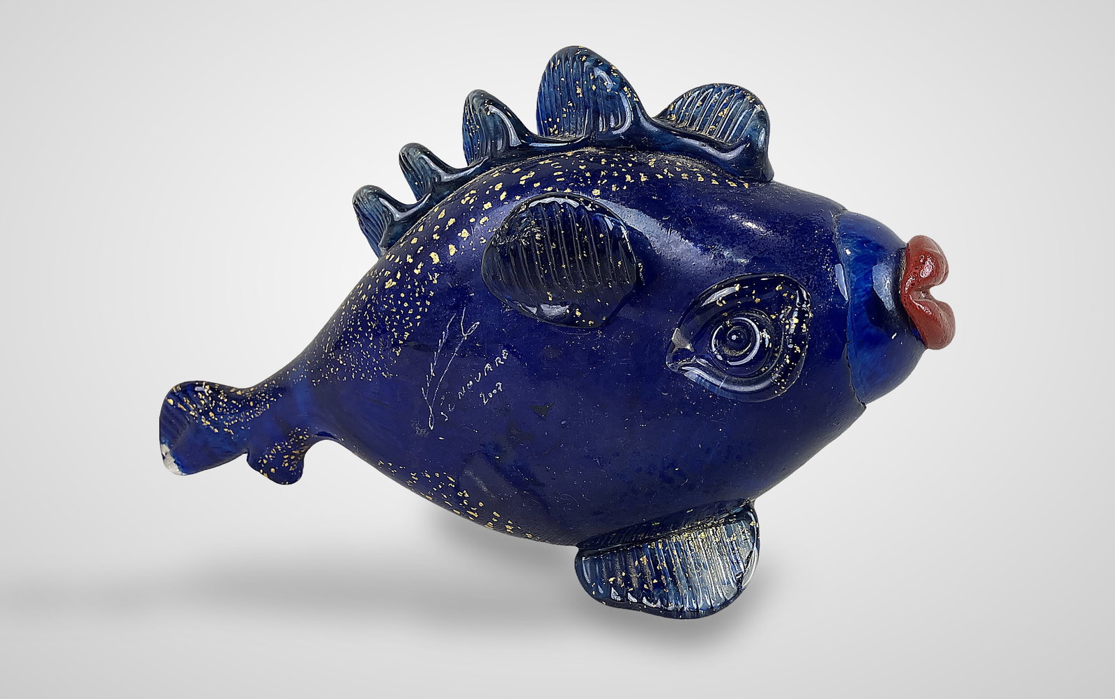 Jean-Claude Novaro Art Glass Fish: This signed art glass fish by the renowned French glassmaker Jean-Claude Novaro (1943â€“2014) is crafted from deep cobalt-toned blue glass infused with luminous gold flake. Novaro is