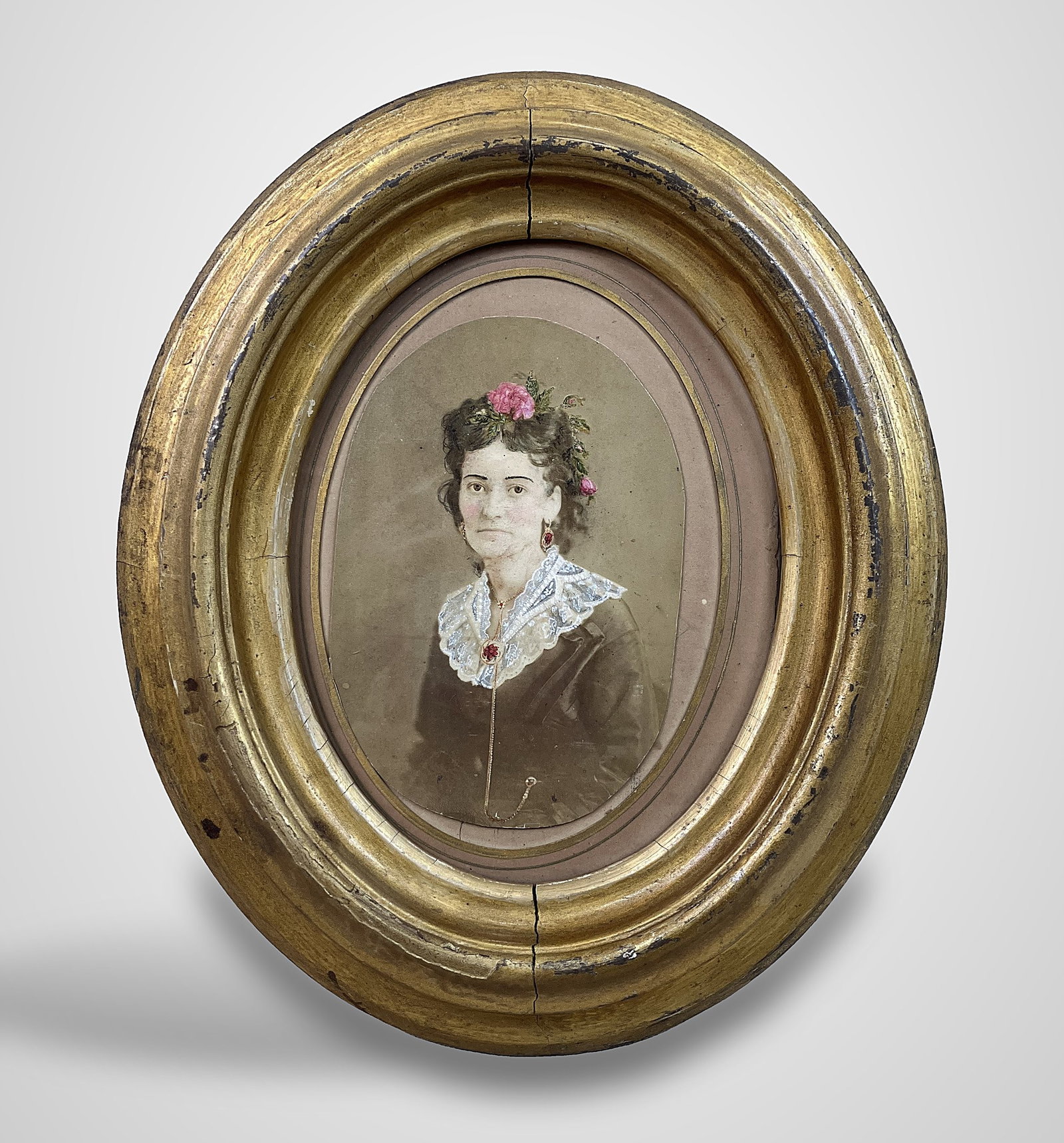 19th-Century Hand-Embellished Portrait of a Woman: Hand-painted photograph depicts a 19th-century woman in traditional attire, wearing a floral necklace and earring demi-parure, with a flower adorning her curly coiffure. It is housed in an oval gilt