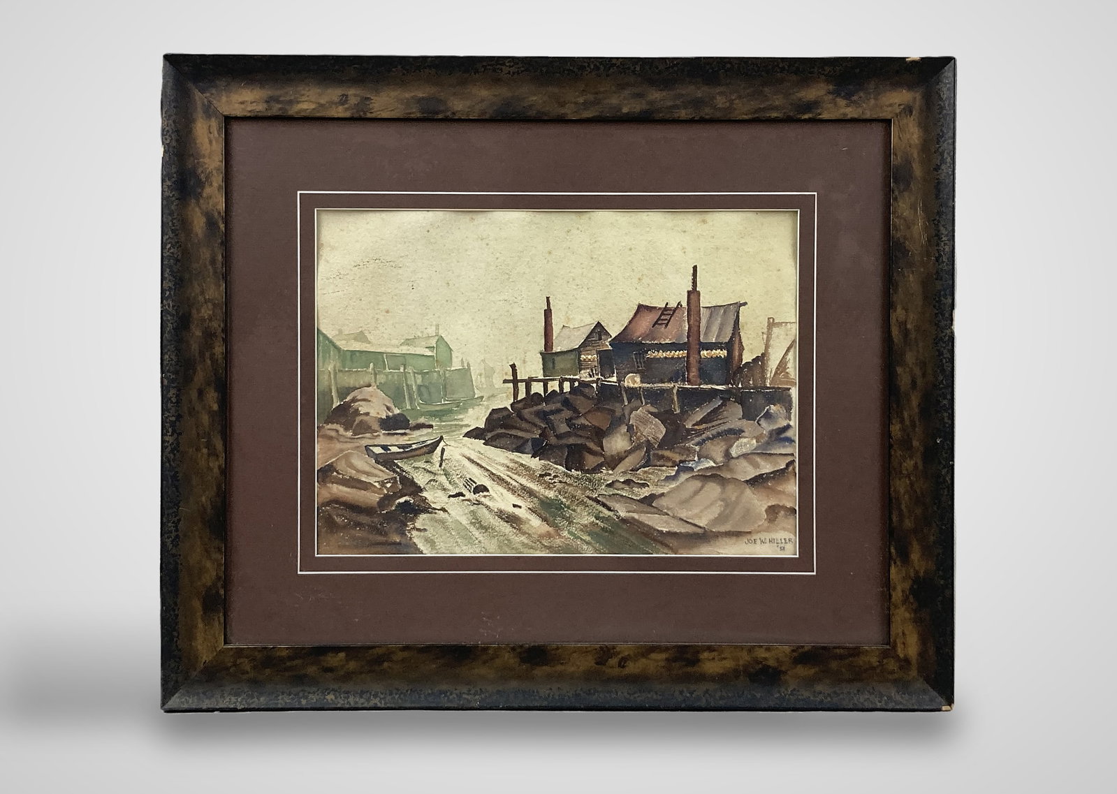 Joe W. Hiller, Industrial Dock Landscape, Watercolor Painting: This mid-20th-century watercolor painting depicts a rustic town nestled alongside a river. The composition highlights buildings situated on stilts both in the background and on the right, accompanied 