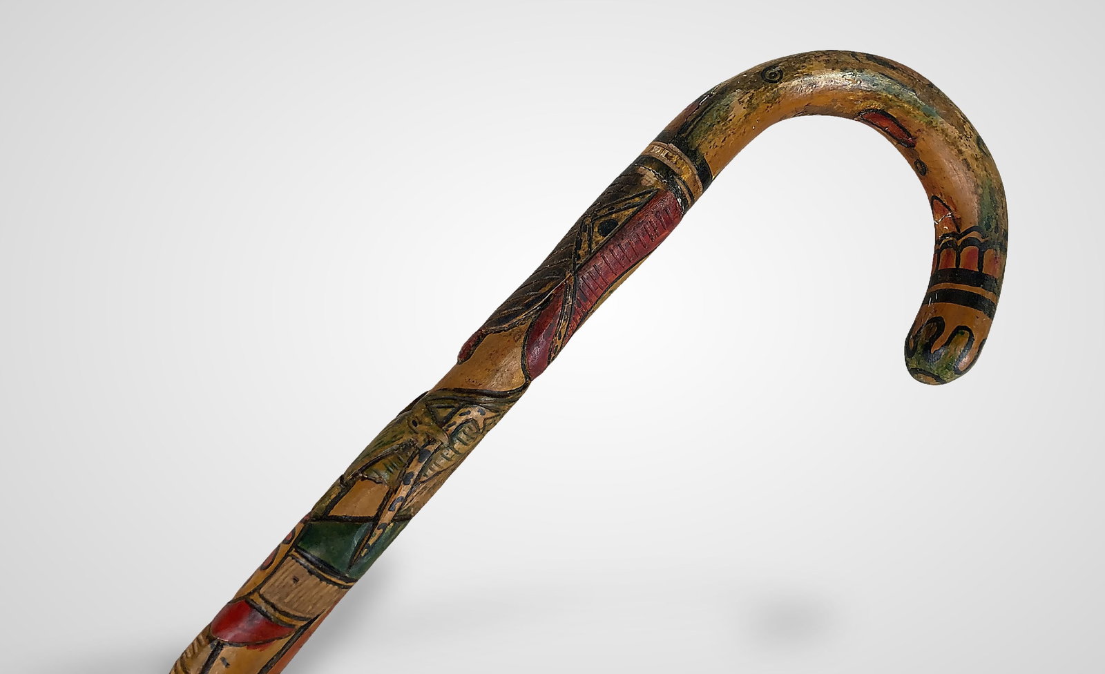 Mexican Folk Art Carved Cane: This intricately carved folk art cane features detailed Aztec-inspired patterns. Near the top, it depicts an eagle with a snake in its mouth; below this is an Aztec warrior adorned in a large
