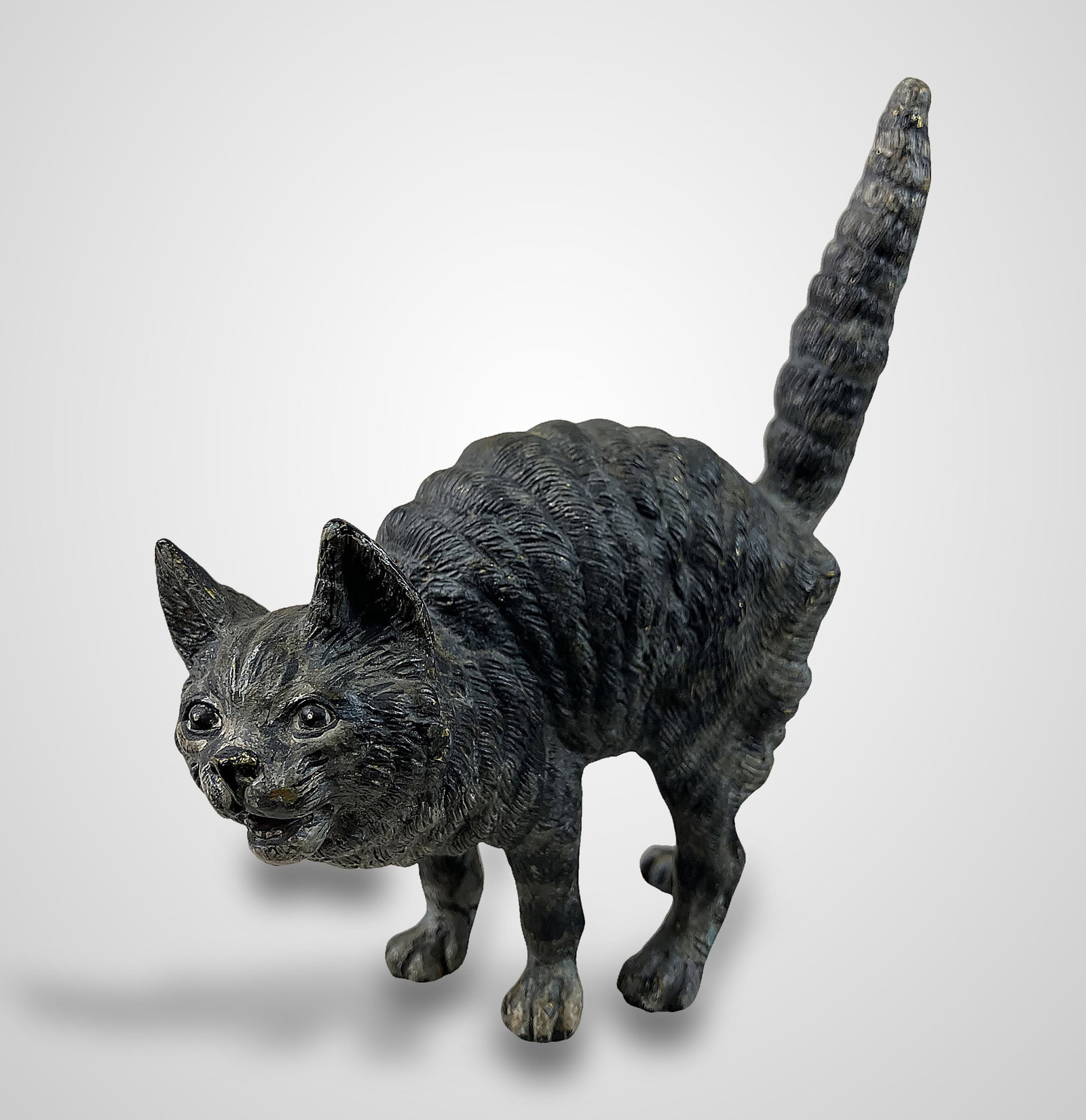 Austrian Cold Painted Bronze Cat: This piece, created in the Austrian taste of slightly larger miniatures, possesses engaging and lively features. The cat is depicted with an open mouth, wide eyes, standing fur, and an extended tail.