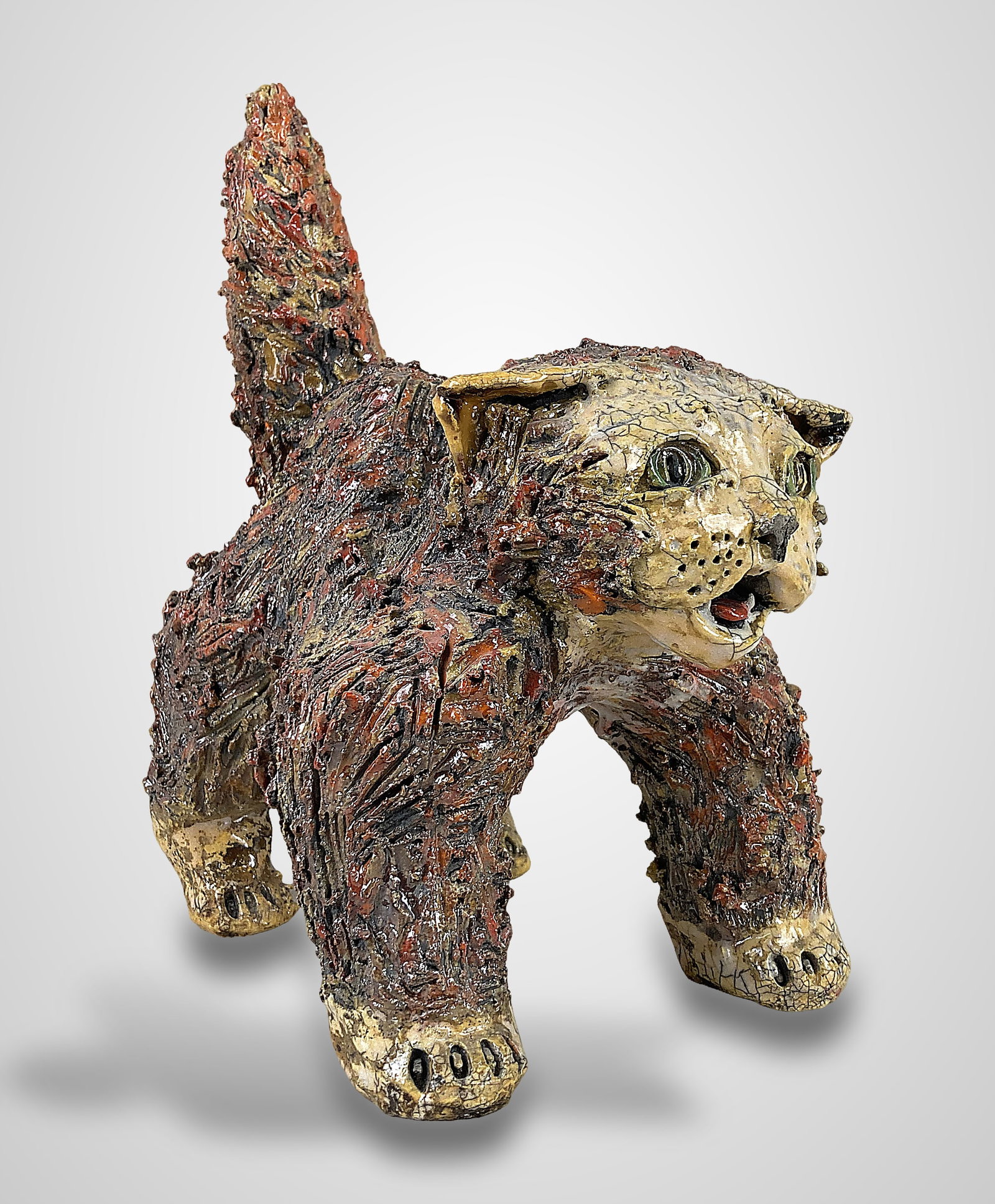 Raku Pottery Cat Sculpture: This handmade studio pottery sculpture captures a vocal cat in a defensive, wide-set stance, featuring an erect tail and an open, expressive mouth. The piece is heavily textured with deeply incised