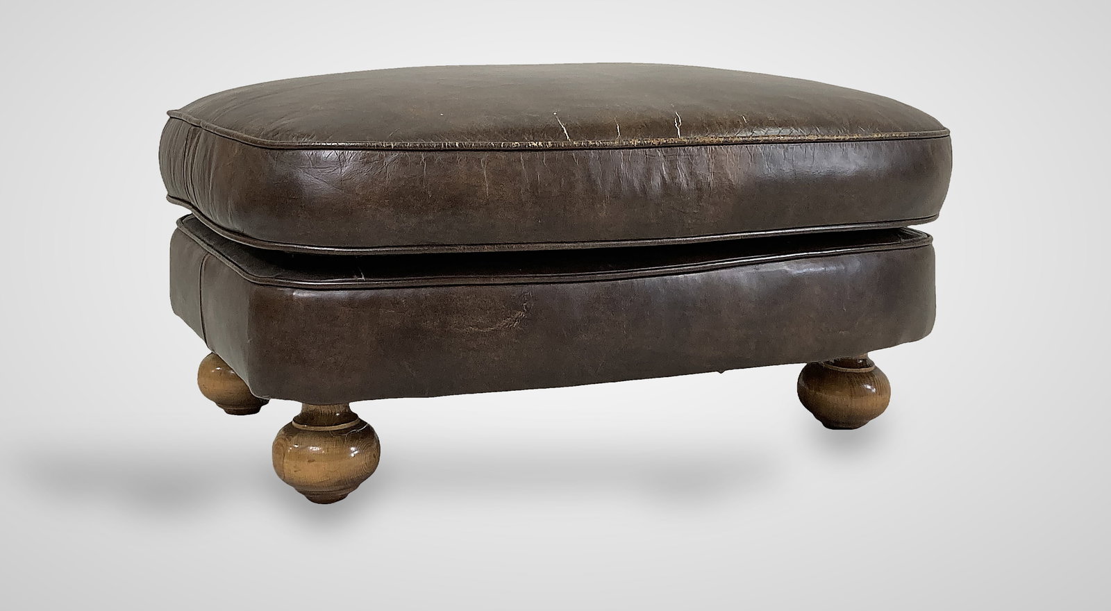Brown Leather Ottoman: Ottoman features rich brown leather throughout, offering a rustic and handsome aesthetic. It is supported by lighter wood bun feet and measures 14 1/2 in. H x 30 in. W x 25 3/4 in. D. It is in good