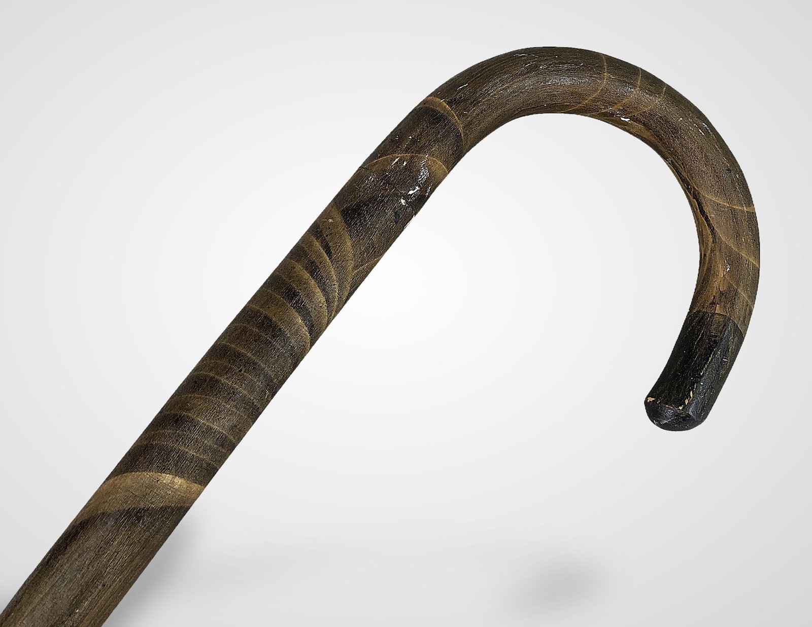 Antique Folk Art Crook Handle Cane: This classic, polished crook-style cane features a smoothly curved handle and a distinct decorative grain pattern with dark stripe accents. It exhibits a worn patina and measures approximately 36 in.