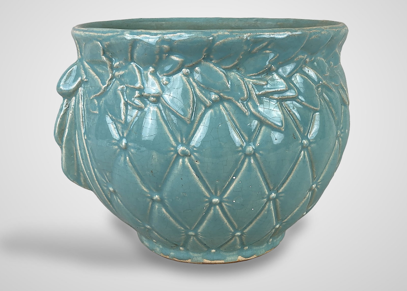 McCoy Pottery Tierra Cushion Jardiniere: This McCoy pottery piece features a sophisticated diamond-quilted body pattern accented by small relief dots. The design is further detailed with an overlapping leaf-and-berry rim trim and sculpted