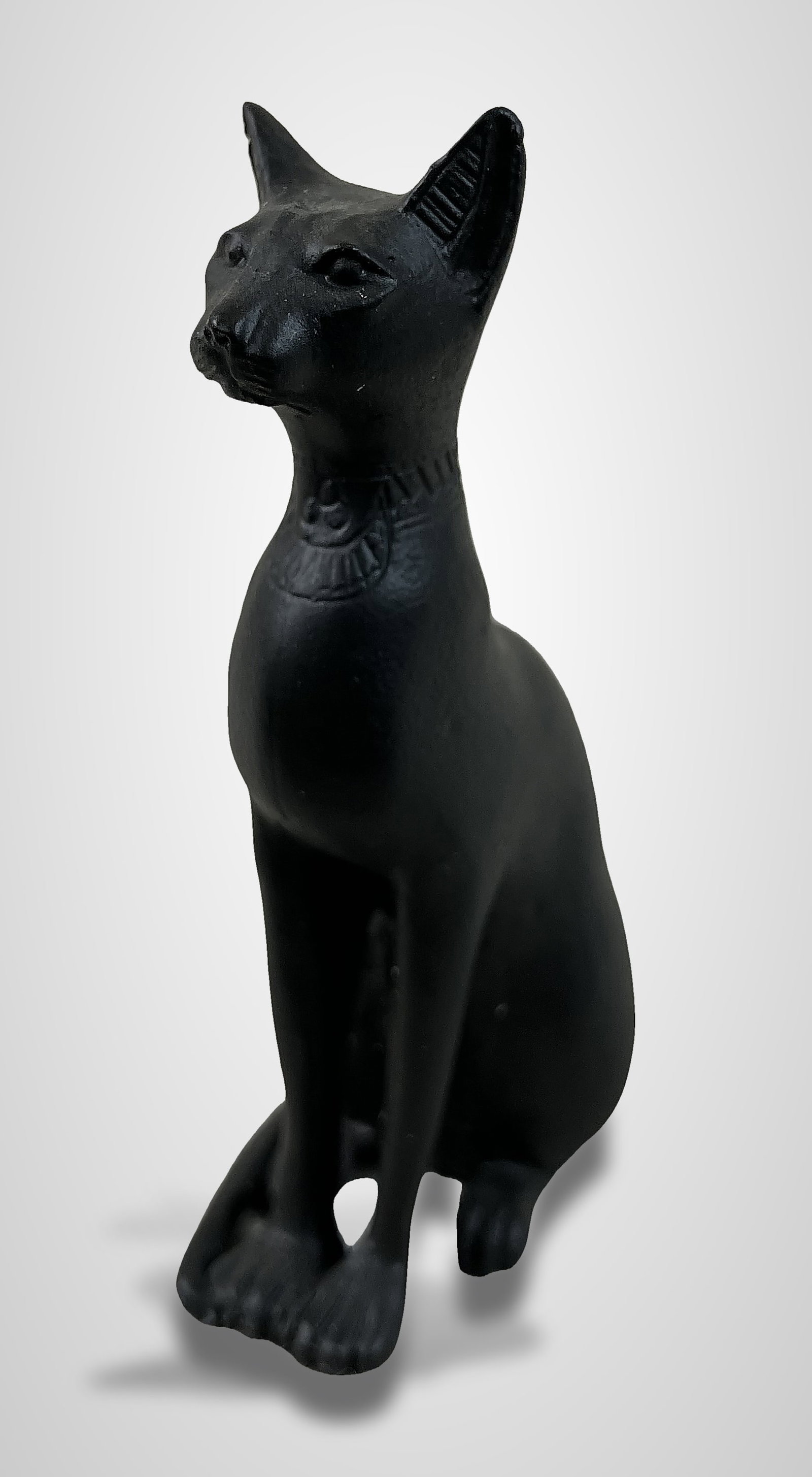 Bastet Egyptian Cat Miniature: Elegant and refined miniature figurine depicts Bastet, the Egyptian goddess of cats. Crafted from cast metal, likely iron, it features a dark finish. The piece measures approximately 2 3/8 in. H x 1 1