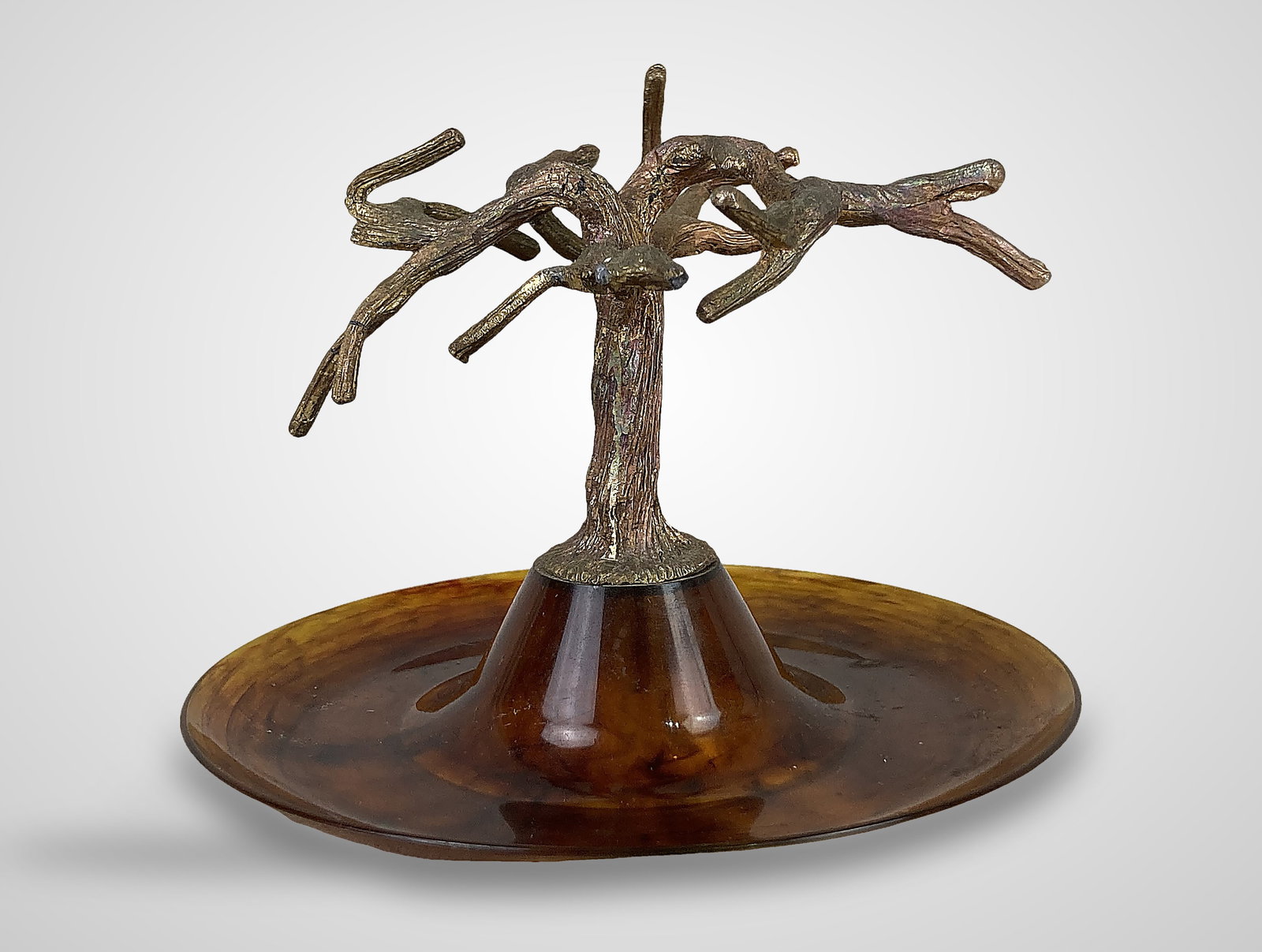 Vintage Vanity Tree Ring Holder: This vanity accessory features a dish base crafted from faux amber-brown tortoiseshell resin, which is topped with a central cast-metal tree designed for hanging rings. The piece measures