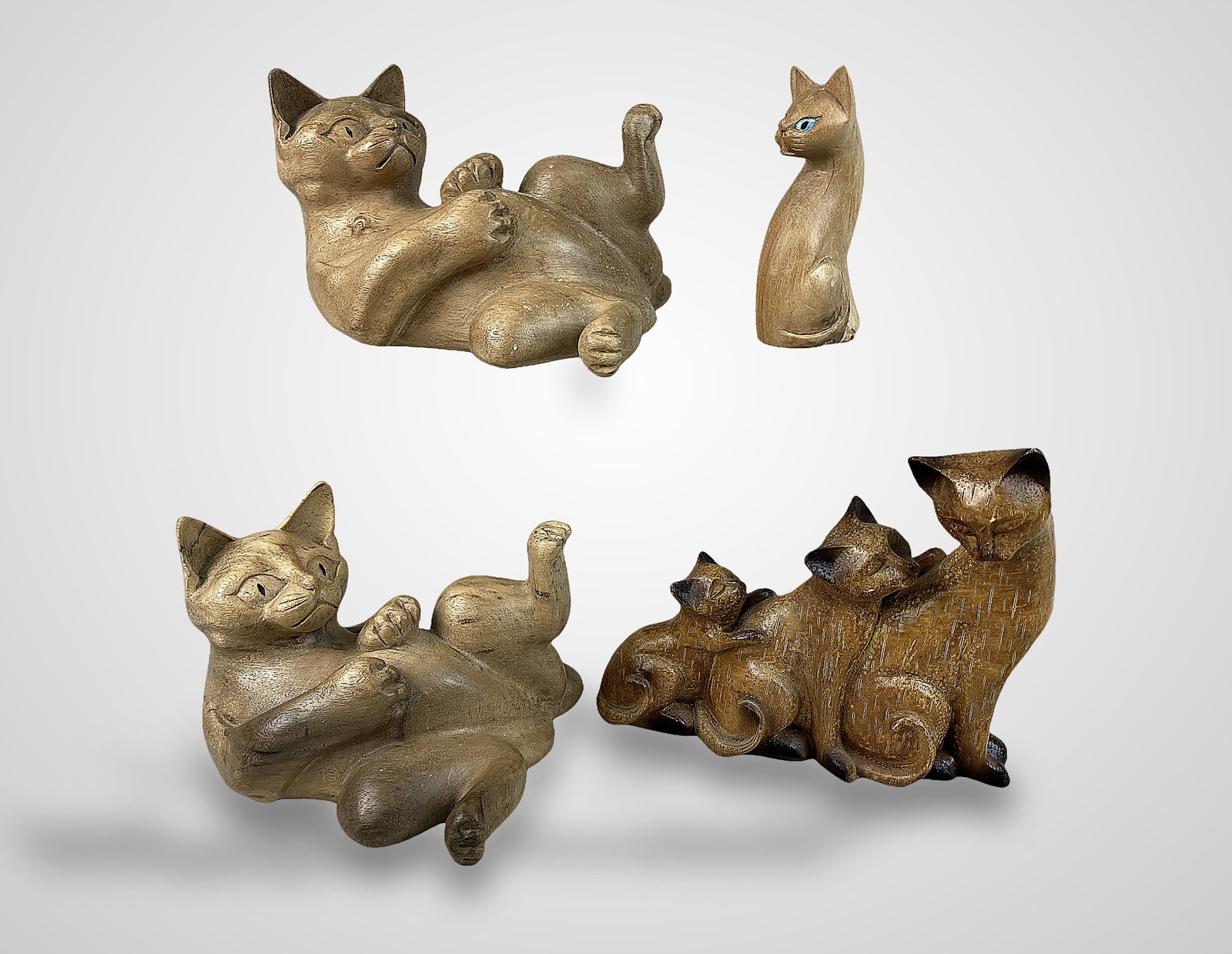 Folk Art Carved Wood Cat Figurines: Group of four finished wood figurines exemplifies hand-carved folk artistry. The collection features various textures, with some pieces smoothly sanded and others with a finished wood surface. The lar