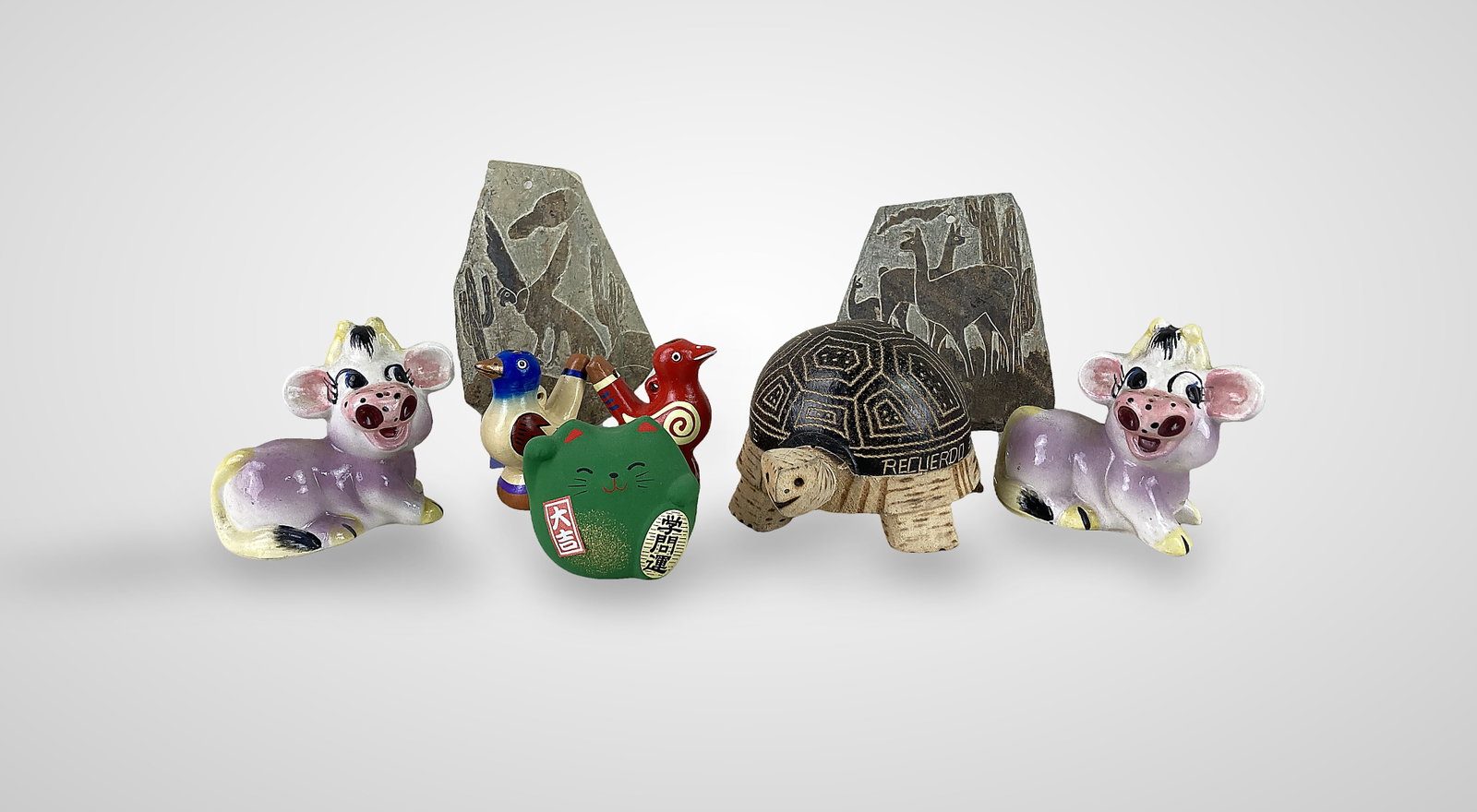 Assortment of Animal Figures: Eight animal themed items including a Peruvian driftwood with pyrography details and the words Recuerdo Bora Iquitos Peru with a seed rattle mechanism, two petroglyph carved rocks with one depicting a