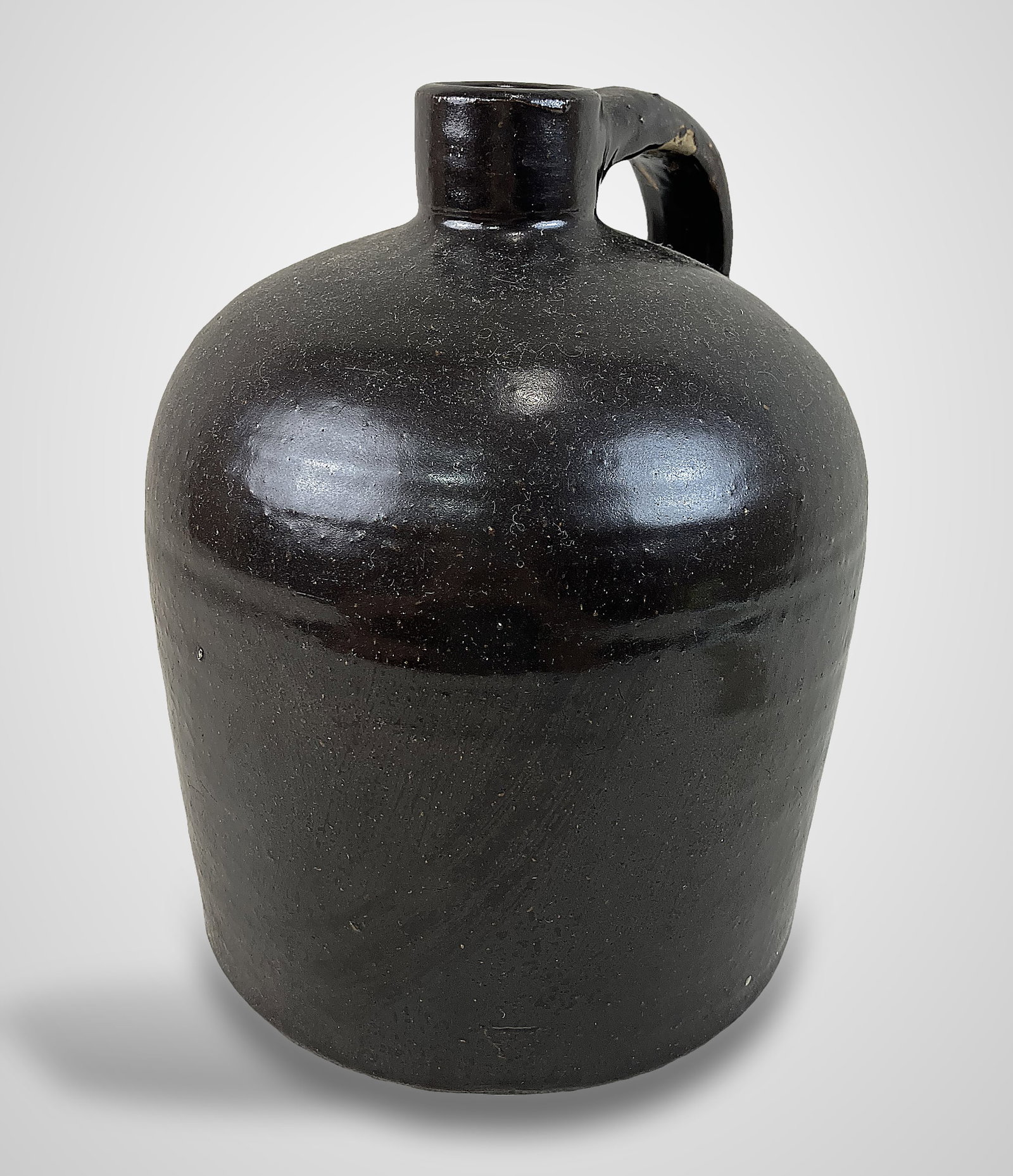 Albany Slip Stoneware Jug: Classic stoneware jug features the signature deep brown Albany slip glaze, complete with an applied handle and a graceful, curving shoulder. It measures approximately 10 3/8 in. H x 7 1/2 in. in diame