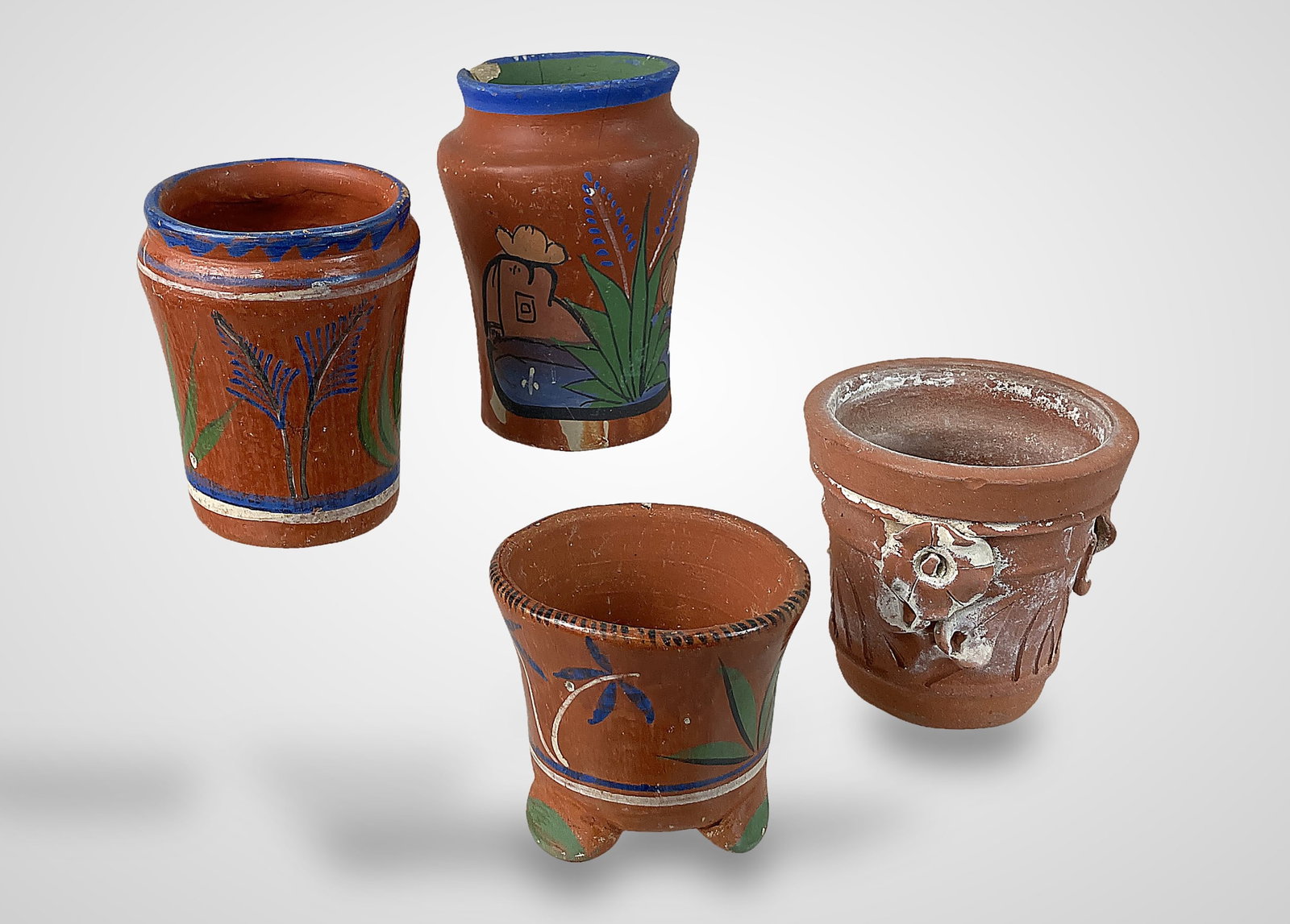Mexican Folk Art Pottery Vases: This group of four cantarito vases exemplifies traditional Mexican folk artistry through carefully molded forms and detailed decorative work. The set includes one vase featuring floral relief, one