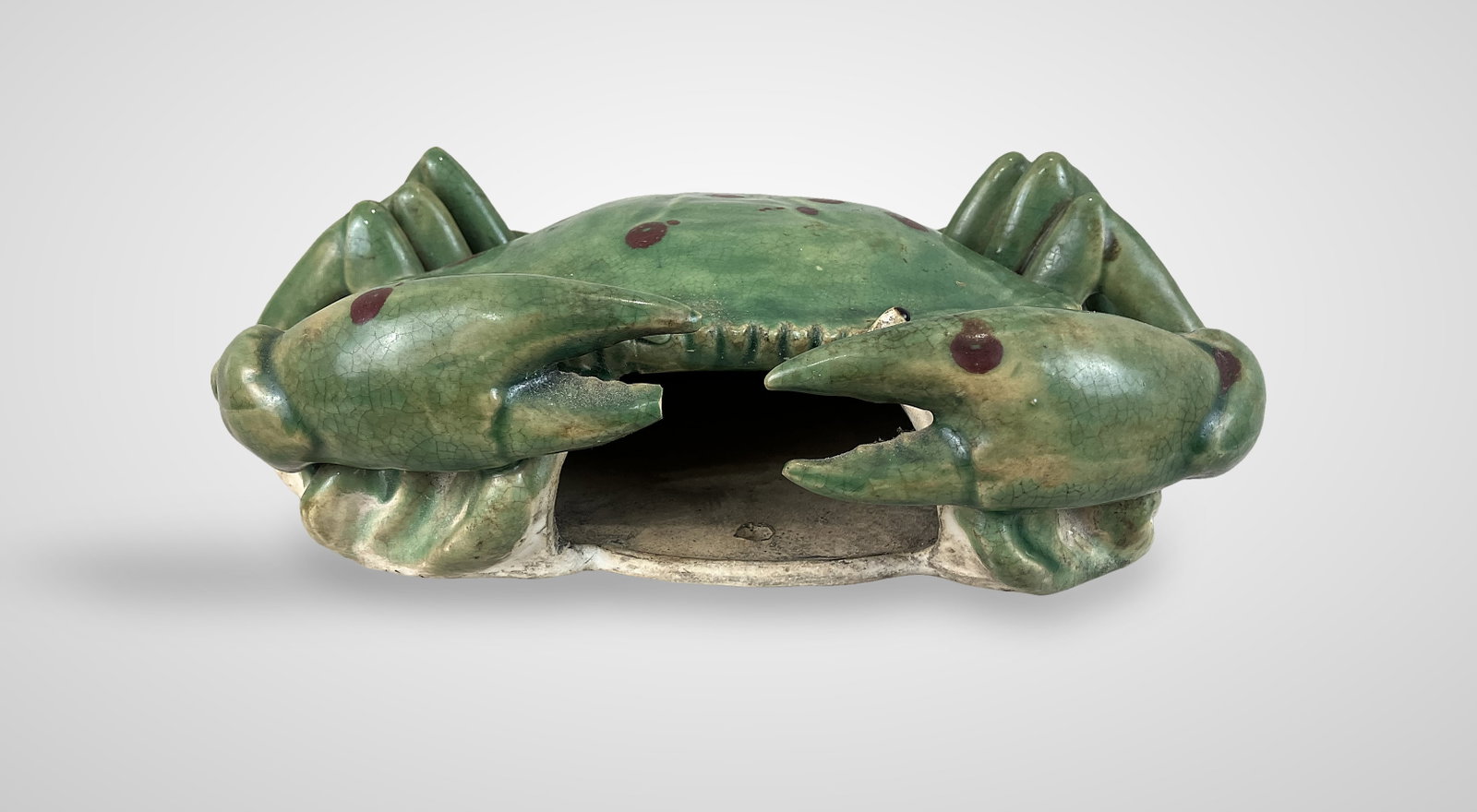 Ceramic Crab Wall Planter: Wall-hanging planter is crafted in the form of a glazed ceramic crab, featuring a green body accented with vibrant red spots. The piece measures approximately 7 in. H x 10 1/2 in. W x 3 3/4 in. D.