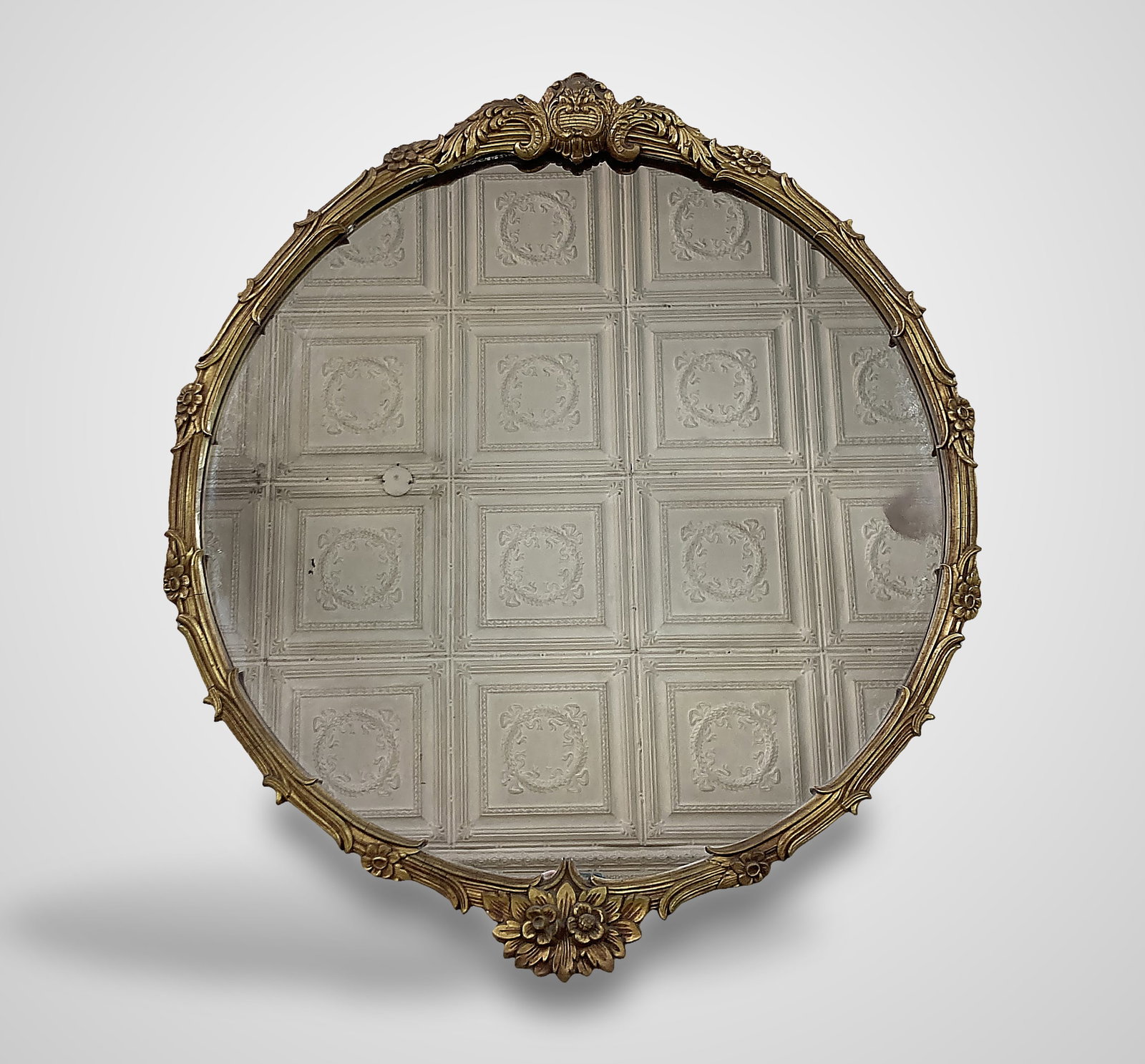 Rococo Revival Gilt Mirror: 19th-century mirror is a refined interpretation of the classic Louis XV Rococo era. The circular frame features an applied central crest accented by rosette forms, with linear styling and grass