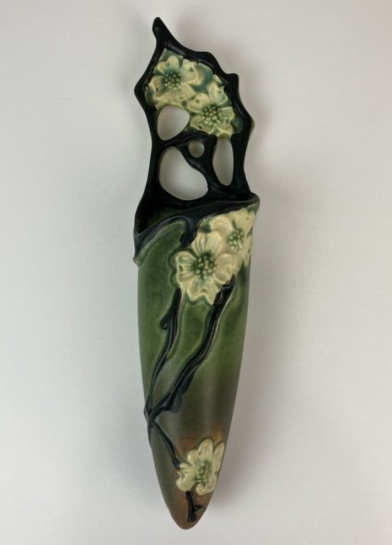 Roseville Pottery Dogwood Wall Pocket: This 1920s Roseville art pottery wall pocket features the classic Dogwood pattern with a reticulated design accented by flowers, finished in rich green tones with a matte glaze. Measuring