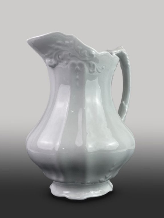 Ironstone Pitcher: This 19th-century ironstone pitcher by Johnson Brothers features an elegant combination of embossed scrollwork and bellflower designs. The piece is characterized by a ribbed form, a flared scalloped l