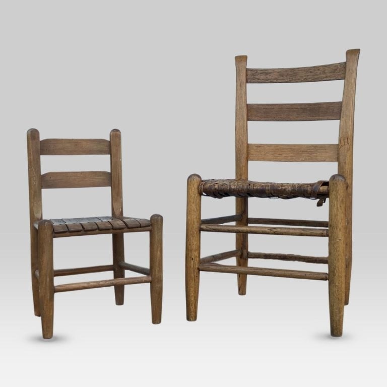 Two Country Ladderback Chairs: Two country oak ladderback chairs, comprising a small chair with a woven seat and a child's chair with a slat seat, both featuring sturdy country forms with a rich patina; the small chair measuring