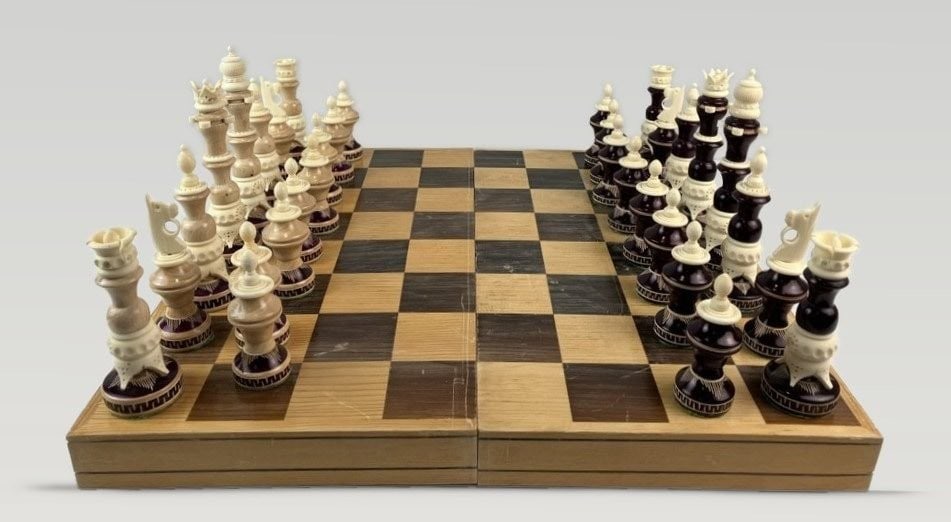 Vintage Chess Set: This marquetry chess board is crafted from natural and dark wood and comes with a set of richly adorned chess pieces in ivory tones. The board measures approximately 1 5/8 in. H x 17 in. W x 17 3/8 in