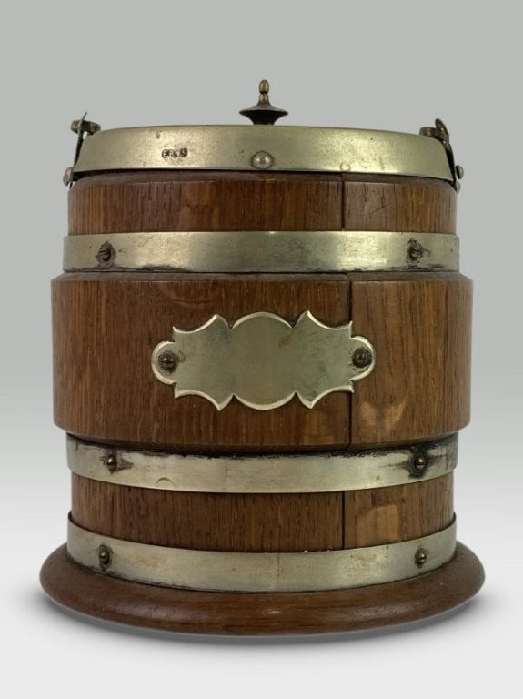 Early 20th Century Biscuit Barrel: Classic biscuit barrel features an oak wood construction accented with gilt silver plate mounts marked EPNS (electroplated nickel silver) and a fitted porcelain interior. It measures approximately 7 i