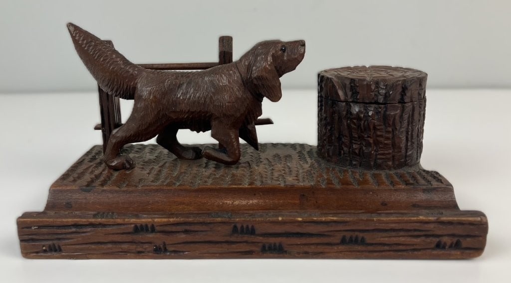 Carved Folk Art Hunting Dog Inkwell Stand: This late 19th-to-early 20th-century folk art inkwell stand features a rich, dark wood patina and charming hand-carved details. The sculptural scene depicts a hunting dog approaching a fence near a