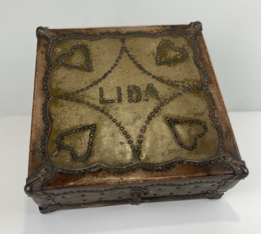Folk Art Leather Decorated Box: Decorative wooden box is wrapped in rich leather and accented with intricate brass nailhead (tack) ornamentation along the edges and seams. The hinged lid features a personalized monogram flanked by
