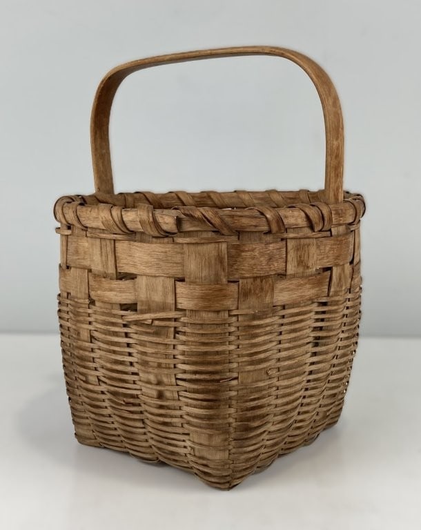 Country Gathering Basket: This splint oak gathering basket features a traditional round rim, a square base, an integrated handle, and a wrapped rim. Measuring approximately 10 1/2 in. H x 8 1/4 in. W x 8 1/8 in. D, the piece
