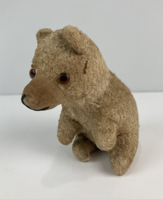 Mid-20th-Century Mohair Teddy Bear: Endearing mid-century miniature teddy bear captures the nostalgic charm of classic vintage plush toys, featuring a warm golden mohair coat and expressive amber glass eyes. The cozy, compact companion