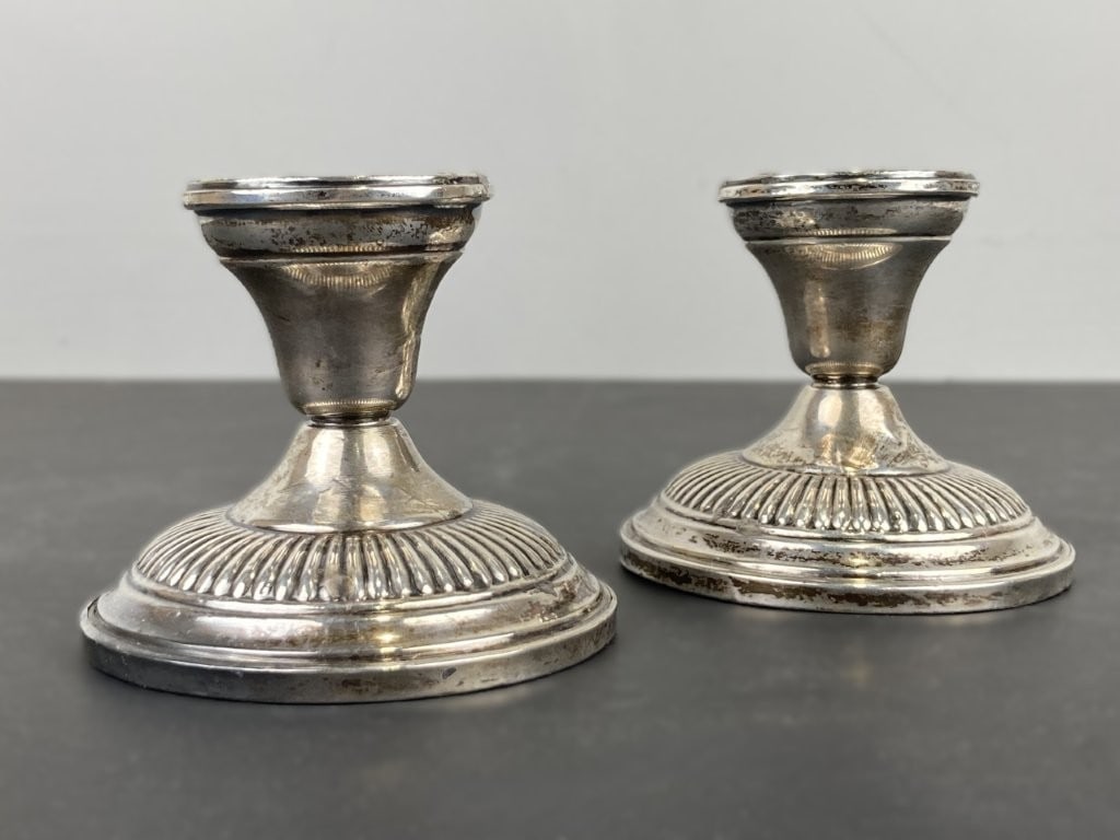 Pair of Hamilton Weighted Sterling Candlesticks: This pair of weighted sterling silver candlesticks is crafted by the Hamilton Silver Co. and features a ribbed design around the base, a tapered waist, and a flared rim socket. Stamped "Hamilton