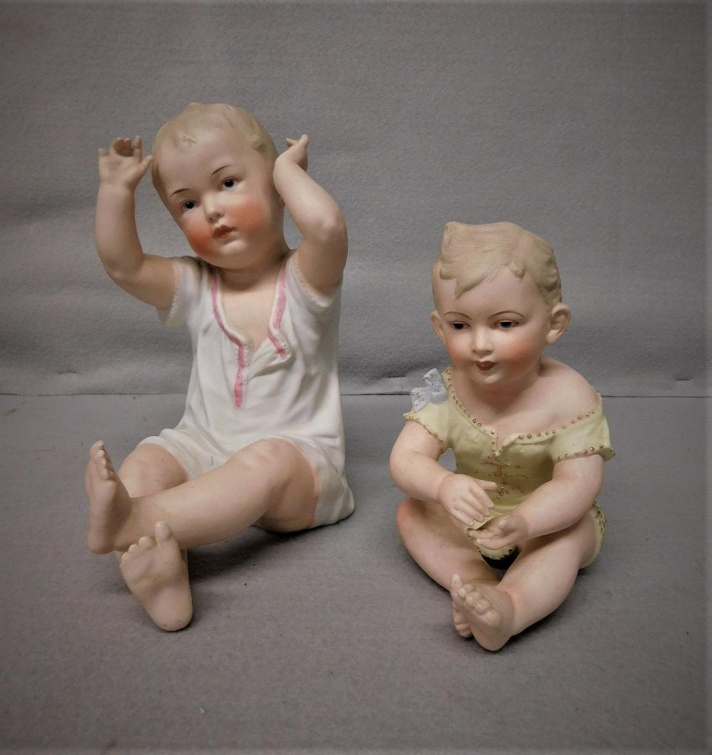 2 Bisque Piano Babies: Lg. 8in. Heubach Sitting Piano Baby (missing tops of 2 fingers); Sm. Sitting#6966 Piano Baby (all good)