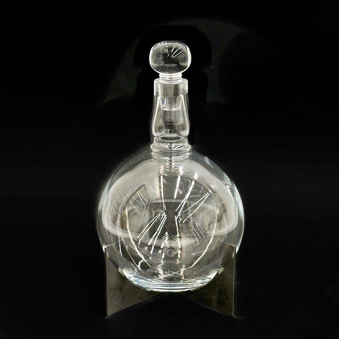 Baccarat Heritage Paraison Glass & Steel Decanter: Baccarat Heritage Paraison Glass & Steel Decanter. Geometric metal base to hold decanter. Underside of glass with acid-stamped Baccarat mark, numbered 23, edge of stand marked Baccarat. Weight: Approx