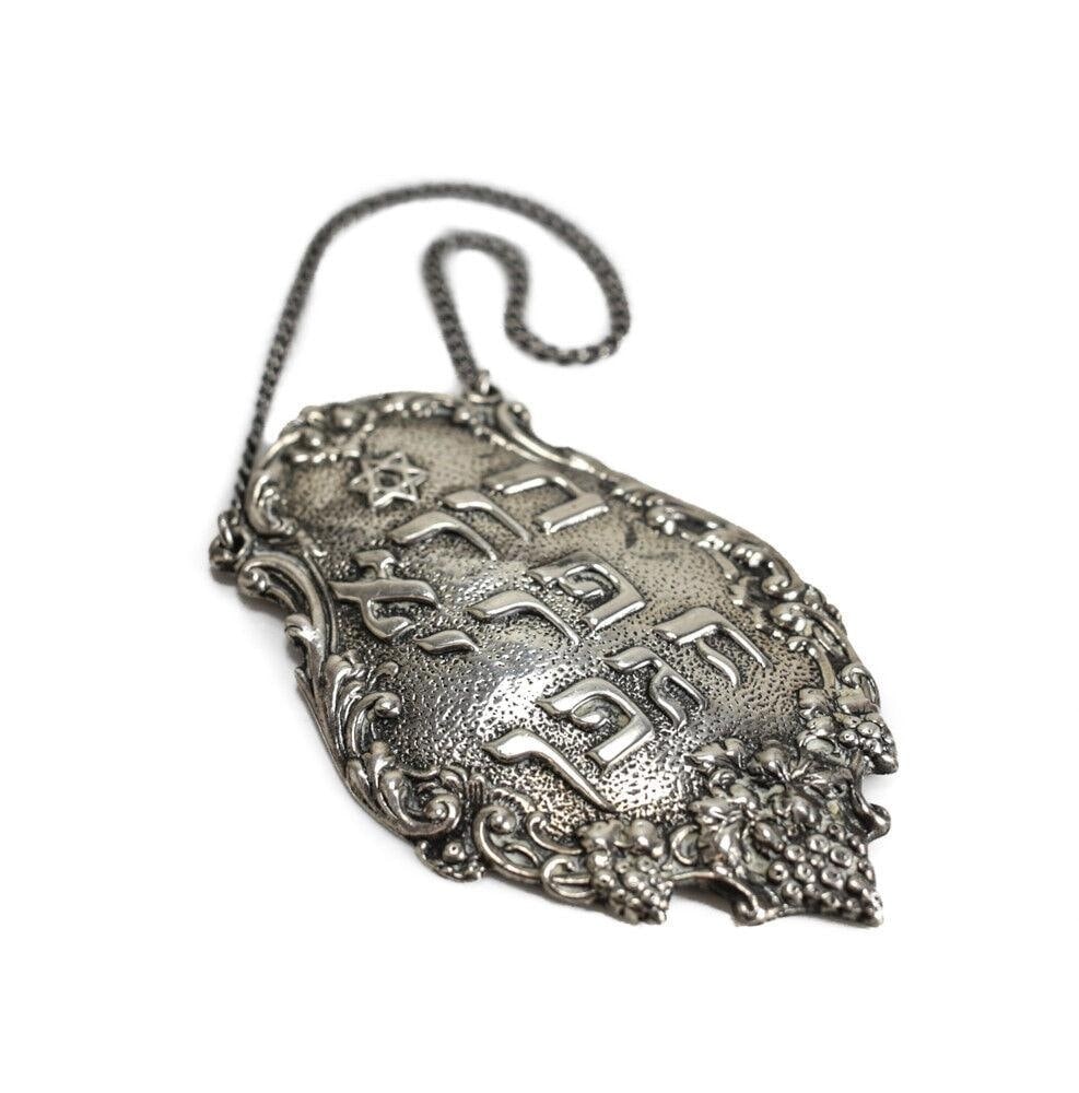 Sterling Silver Judaica Shabbat Wine Bottle Tag Label with chain Hand chased: Sterling Silver Judaica Shabbat Wine Label. Hand chased details. Marked 'Sterling'. 30.9grams Measurements: Approx. Label 3" x 1.875", Chain drop 2.75" Condition: Great condition with some light surfa