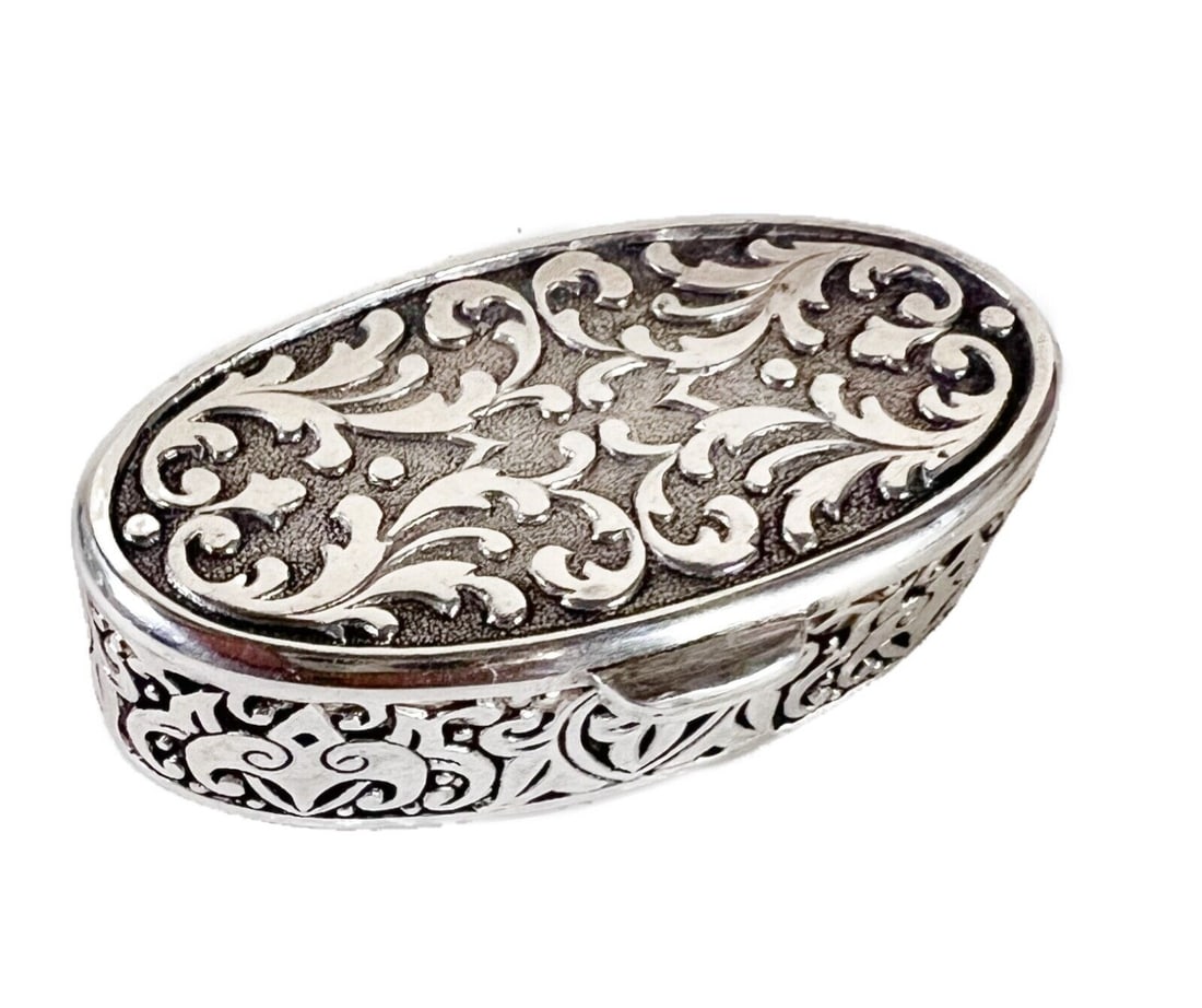 English Sterling Silver pill trinket box JS & Co. 1983: Small Sterling Silver pill or trinket box with gilt interior. Hand chased foliate scrolls. Hallmarks, JS & Co. London 1983 Measurements: Approx. 15.14 grams. 1.625 x 0.75 x 0.5 inches Condition: Very