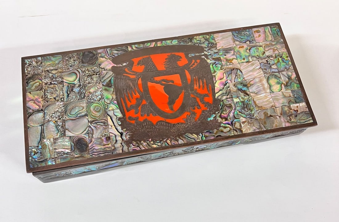 Taxco Copper Mother of Pearl Mosaic Cigarette Box: Taxco Mexico Copper Mother of Pearl Mosaic Box, mid century, armorial with red stone inlay. Wood lined. Measures Approx. 10.375 x 4.75 x 1.25 inches Domestic Shipping: $35