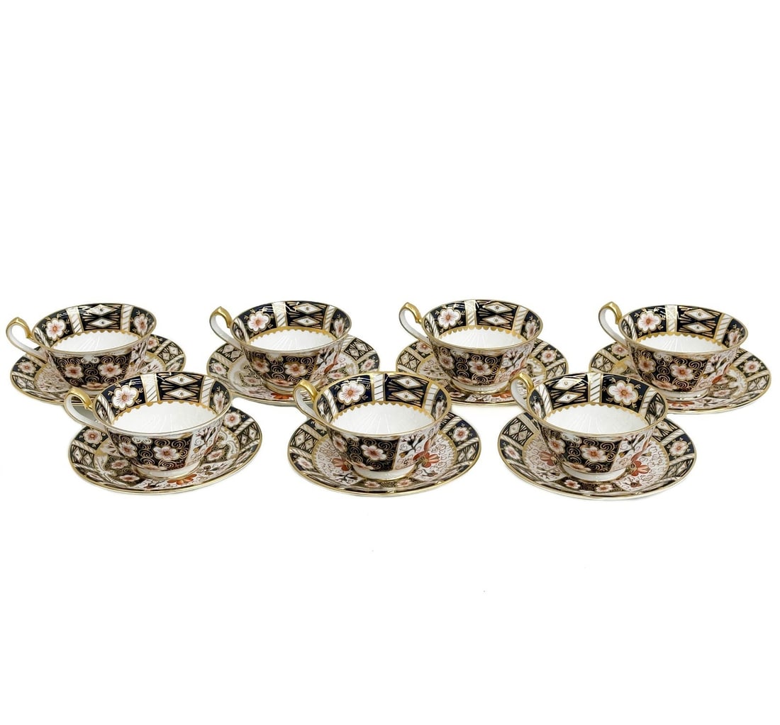 7 Royal Crown Derby Imari #2451 Porcelain Cup & Saucers circa 1932-33: 7 Royal Crown Derby Porcelain Cup & Saucers in Imari pattern #2451. Blue panels, rust flowers, and gold accents. Royal Crown Derby mark to the underside, date mark for 1932-1933. Weight: Approx. 5 lbs